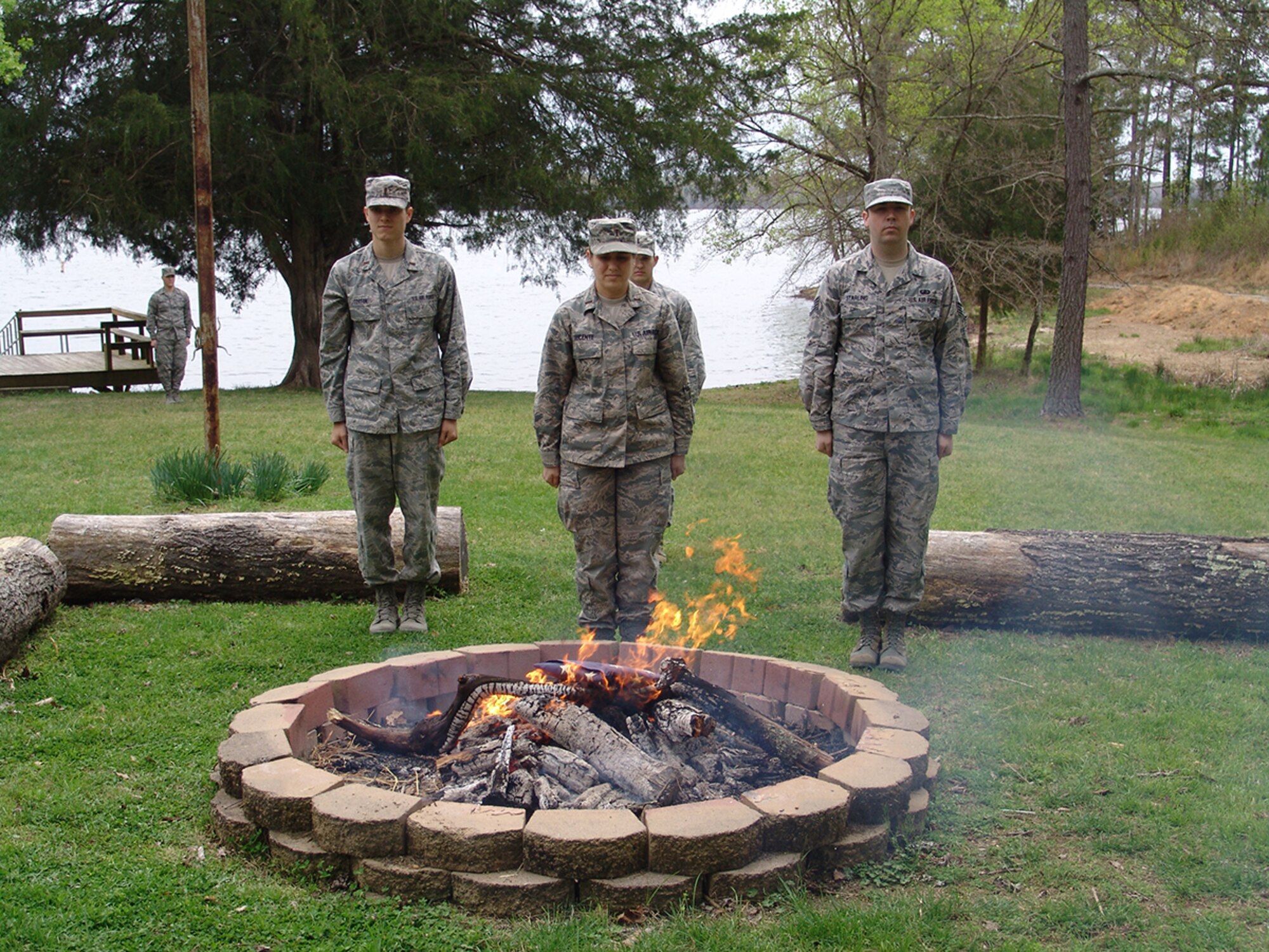 The April 19 flag retirement ceremony at Crockett Cove on Arnold Air Force Base was led by 1st Lt. Joshua Coughenour, Honor Guard Commander, shown standing near the dock, and 1st Lt. Chance Johnson, Detail Commander, back row center. Fellow Guardsmen (left to right) 2nd Lt. Stuart Coston, 2nd Lt. Carlin Lucente and Staff Sgt. Thomas Starling, stand at attention as they pay their final respects to the colors. (Photo by Capt. Sarah Kress)