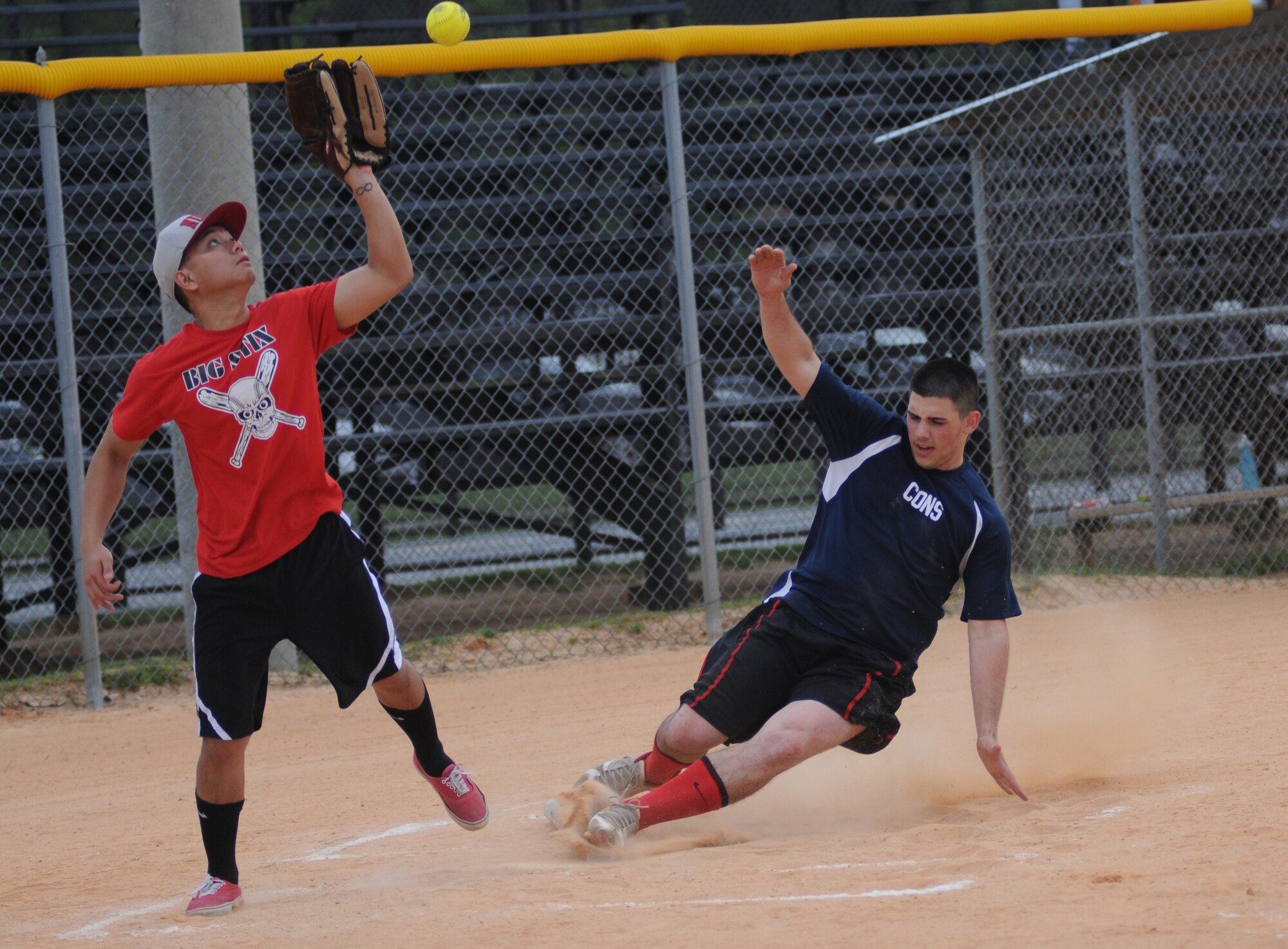 Rogie Dungca, 81st Surgical Operations Squadron catcher, keeps his eye on the ball as Daniel Melecio, 81st Contracting Squadron, slides safely into home plate during an intramural softball game against the 81st Surgical Operations Squadron May 8, 2014, at Keesler Air Force Base, Miss.  81st CONS defeated 81st MSGS, 14-5. (U.S. Air Force photo by Kemberly Groue)