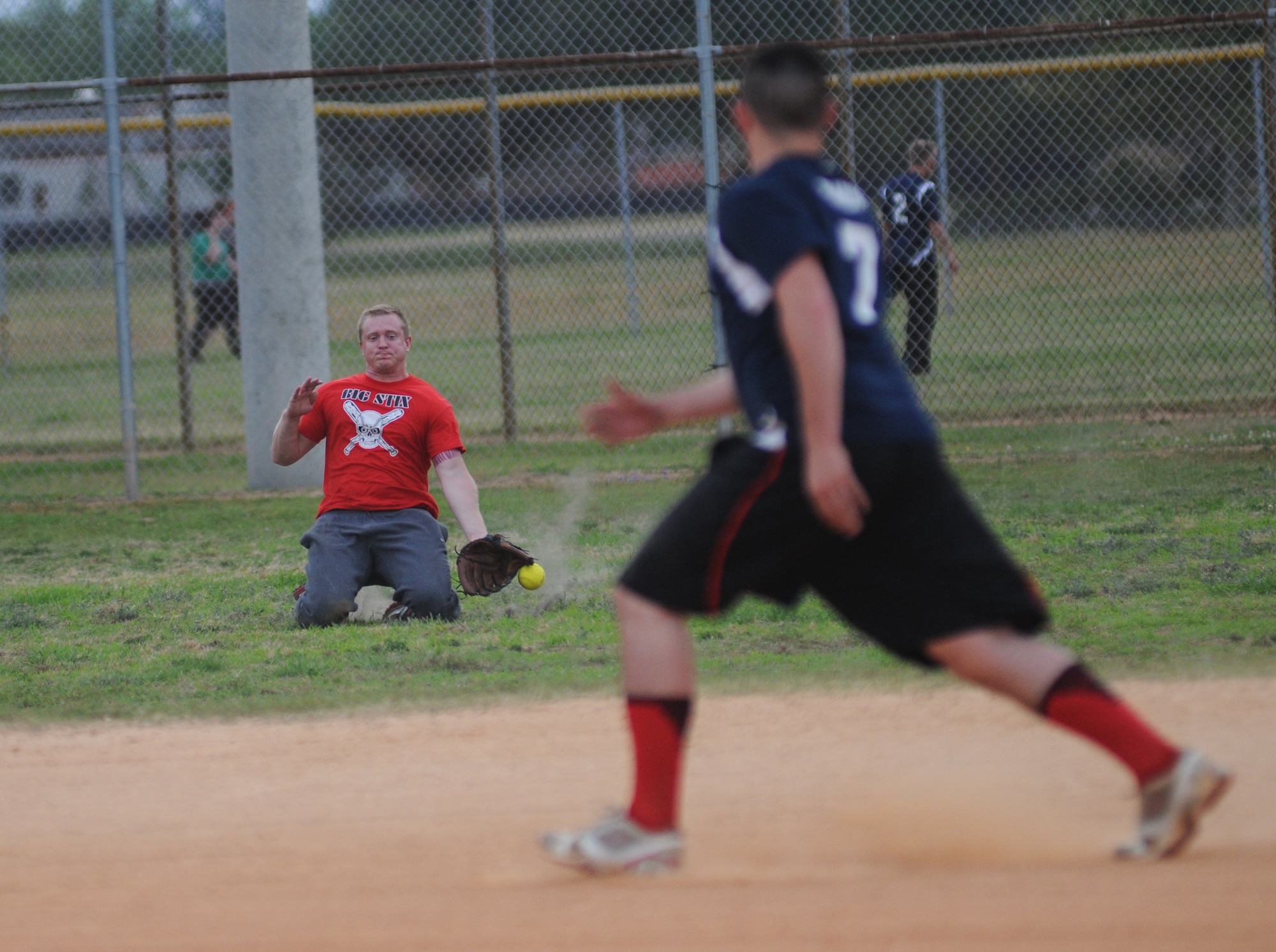 Brennan Roberts, 81st Surgical Operations Squadron, drops to his knees to field the ball in center field during an intramural softball game against the 81st Surgical Operations Squadron May 8, 2014, at Keesler Air Force Base, Miss.  81st CONS defeated 81st MSGS, 14-5. (U.S. Air Force photo by Kemberly Groue)