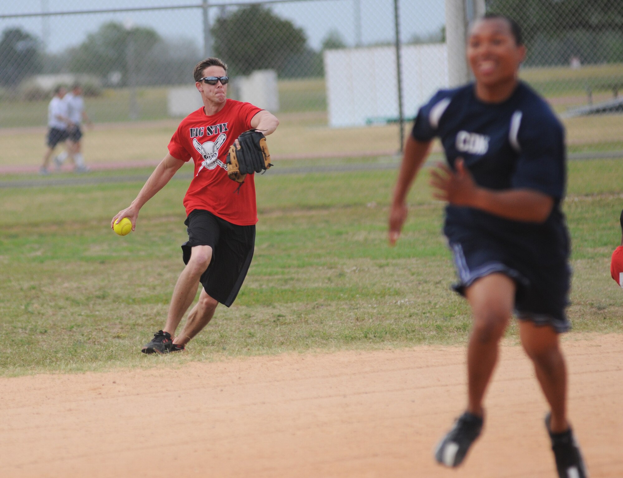 Russell Wians, 81st Surgical Operations Squadron second baseman, prepares to make a throw to first base as Thaddeus Faxon, 81st Contracting Squadron, sprints toward third base during an intramural softball game May 8, 2014, at Keesler Air Force Base, Miss.  81st CONS defeated 81st MSGS, 14-5. (U.S. Air Force photo by Kemberly Groue)