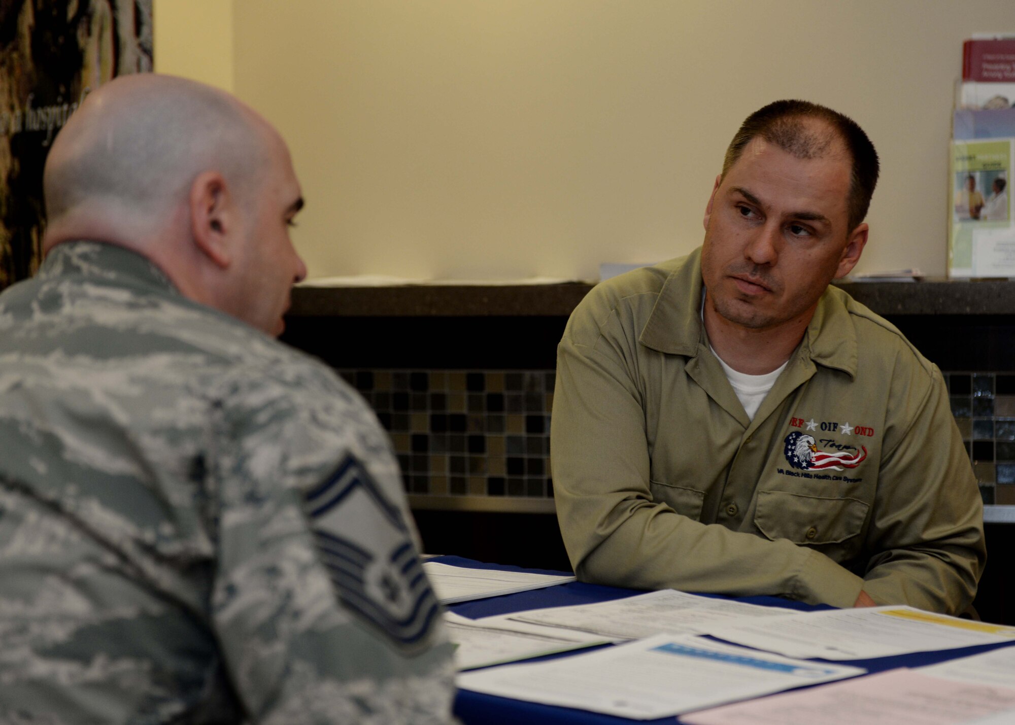 Senior Master Sgt. Charles Sheffield, 28th Medical Group superintendent, visits with Ryan Maurer, South Dakota Veterans Affairs transition patient advocate, to learn about benefits available to servicemembers at the 28th Medical Group at Ellsworth Air Force Base, S.D., May 6, 2014. Representatives from the VA and Pennington County Veterans Services office set up an information booth in the main lobby of the 28th MDG the first Tuesday of every month to help servicemembers get a better understanding of what services are available to them upon separation. (U.S. Air Force photo by Airman 1st Class Rebecca Imwalle/ Released)