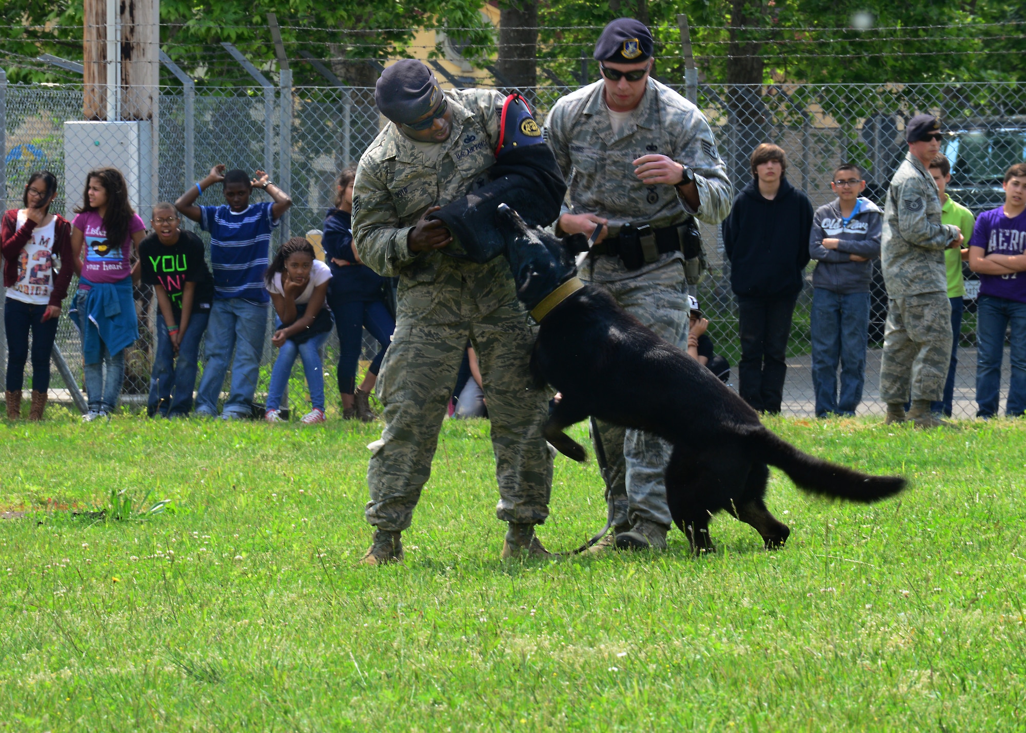 Staff Sgts. Rodriques Boyd and Erik Parris, 31st Security Forces Squadron military working dog handlers, perform a demonstration with Dox, MWD, during an annual job shadow day, May 9, 2014, at Aviano Air Base, Italy. In an effort to create a realistic connection between the classroom and the workforce, Aviano Middle/High School students and young dependents shadowed Airmen from several different career fields. (U.S. Air Force photo/Airman 1st Class Ryan Conroy) 