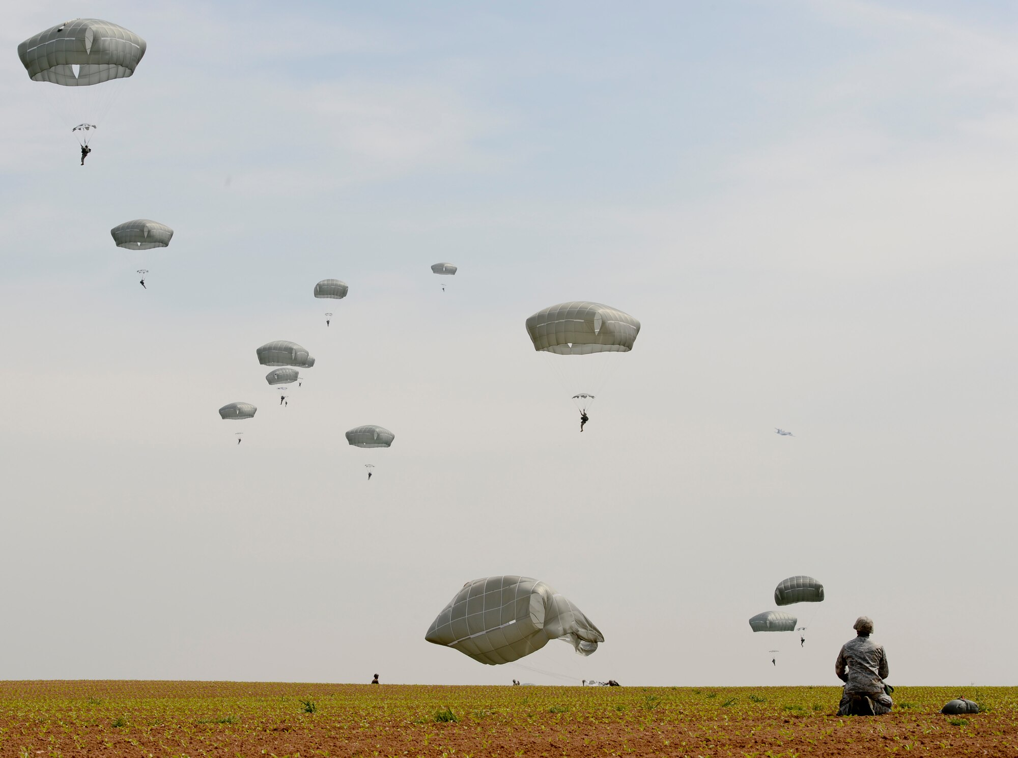 An Airman gazes off into the distance, as he watches paratroopers drop to the ground during International Jump Week in Alzey landing zone, Germany, May 6th, 2014. More than 300 jumpers from nine different nations performed a total of 404 static-line jumps and 132 high-altitude low-opening jumps in three days. (U.S. Air Force photo/Airman 1st Class Michael Stuart)