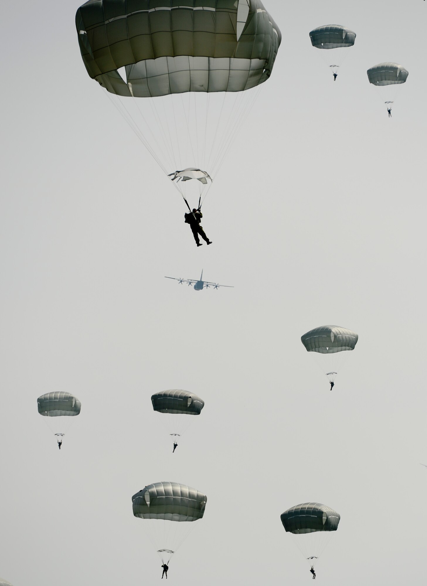 A parachutist descends slowly towards the ground as a C-130 flies off into the distance during International Jump Week in Alzey landing zone, Germany, May 5th, 2014. More than 300 jumpers from nine different nations performed a total of 404 static-line jumps and 132 high-altitude low-opening jumps in three days. (U.S. Air Force photo/Airman 1st Class Michael Stuart)