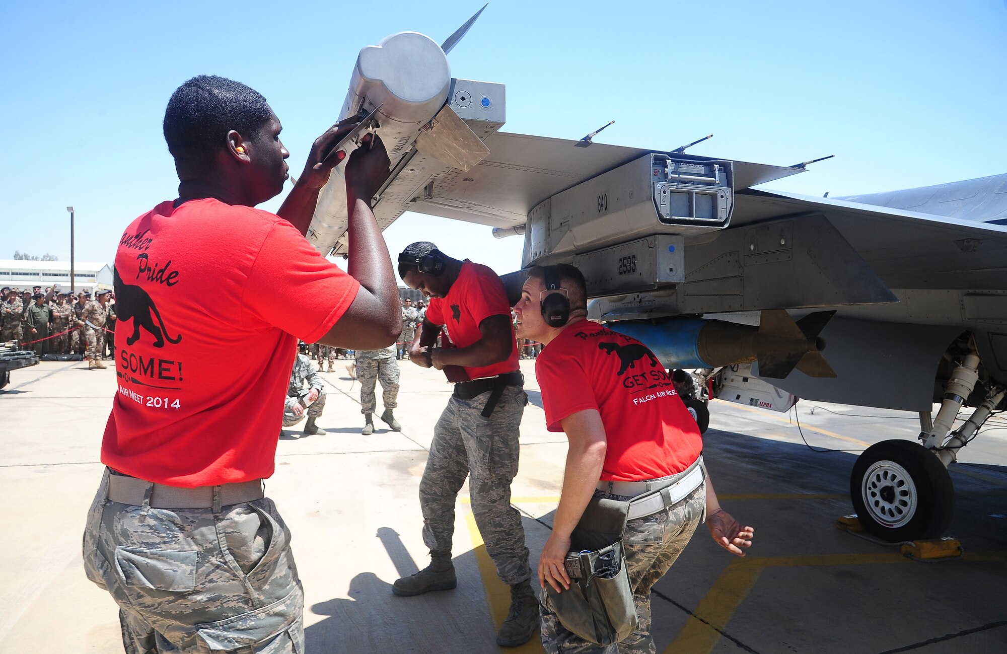 U.S. Air Force Airmen 1st Class Travis Campbell and Keith Enty, and Staff Sgt. Anthony Padilla, all weapons loaders from the 13th Fighter Squadron at Misawa Air Base, Japan, work as fast as they can during a weapons loading competition at Exercise Eager Tiger May 11, 2014, at an air base in northern Jordan. The multi-national exercise featured friendly competitions aimed at building camaraderie among countries. (U.S. Air Force photo by Staff Sgt. Brigitte N. Brantley/Released)