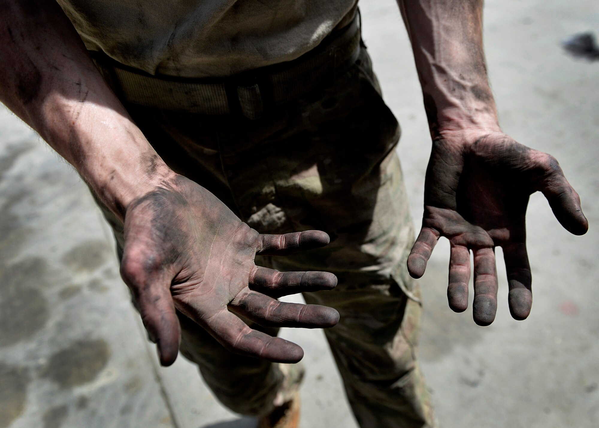 Staff Sgt. Ryan Schmitz, 455th Expeditionary Logistics Readiness Squadron vechicle maintenance journeyman shows off his greasy hands after cleaning a vehicle May 7, 2014 at Bagram Airfield, Afghanistan.  As a vehicle maintainer at here, Schmitz helps ensure more than 350 vehicles are operational and ready for their daily mission.  Schmitz is deployed from Yokota Air Base, Japan and a native of Kimball, Minn. (U.S. Air Force photo by Staff Sgt. Evelyn Chavez/Released)