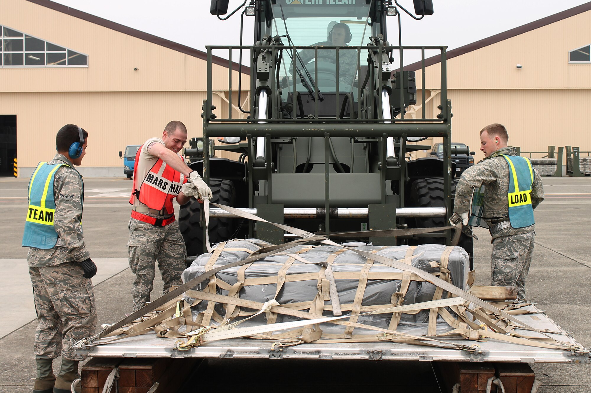 Airmen filling in as augmentees for the 374th Logistics Readiness Squadron unstrap a pallet of supplies during a Samurai Readiness Inspection at Yokota Air Base, Japan, May 13, 2014. The inspection tested Yokota's ability to generate cargo for humanitarian aid and disaster relief contingencies. (U.S. Air Force photo by Airman 1st Class David Danford/Released)