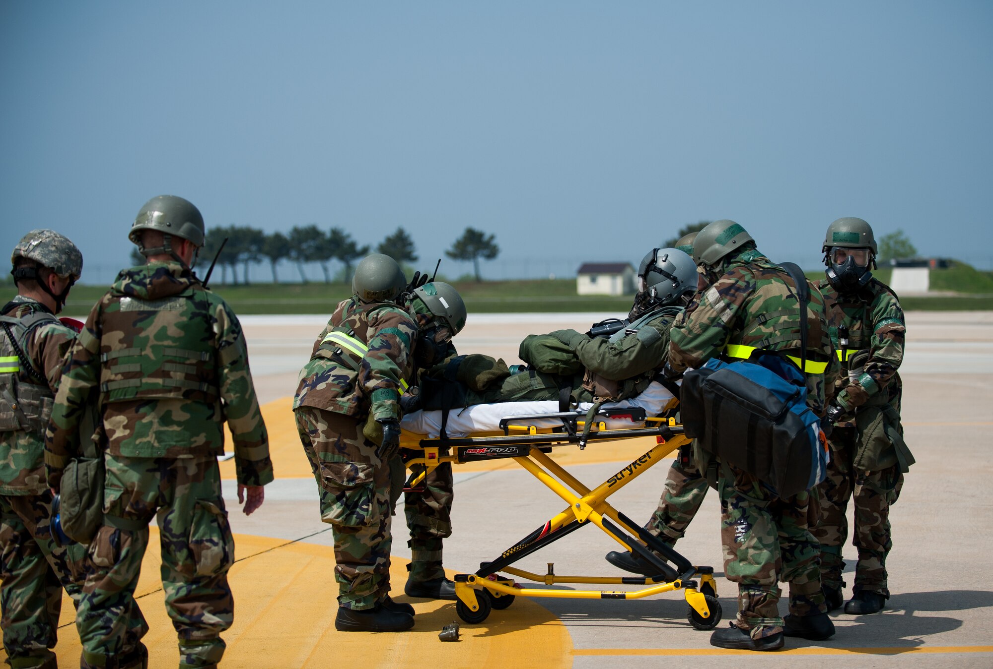 Wing inspection team members observe as Airmen from the 8th Medical Group transport a simulated contaminated pilot during exercise Beverly Bulldog 14-2 at Kunsan Air Base, Republic of Korea, May 9, 2014. This exercise tested the Wolf Pack's ability to perform its mission while under threat of chemical attack. (U.S. Air Force photo by Staff Sgt. Clayton Lenhardt/Released)