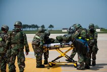 Wing inspection team members observe as Airmen from the 8th Medical Group transport a simulated contaminated pilot during exercise Beverly Bulldog 14-2 at Kunsan Air Base, Republic of Korea, May 9, 2014. This exercise tested the Wolf Pack's ability to perform its mission while under threat of chemical attack. (U.S. Air Force photo by Staff Sgt. Clayton Lenhardt/Released)