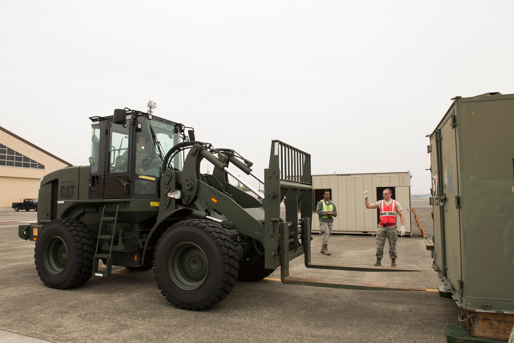 Senior Airman Patrick Bollinger, augmentee, marshals a forklift during a Samurai Readiness Inspection at Yokota Air Base, Japan, May 13, 2014. Bollinger was one of 75 augmentees assigned to help the 374th Logistical Readiness Squadron air transportation operations shop move cargo during the inspection. (U.S. Air Force photo by Staff Sgt. Cody H. Ramirez/Released)