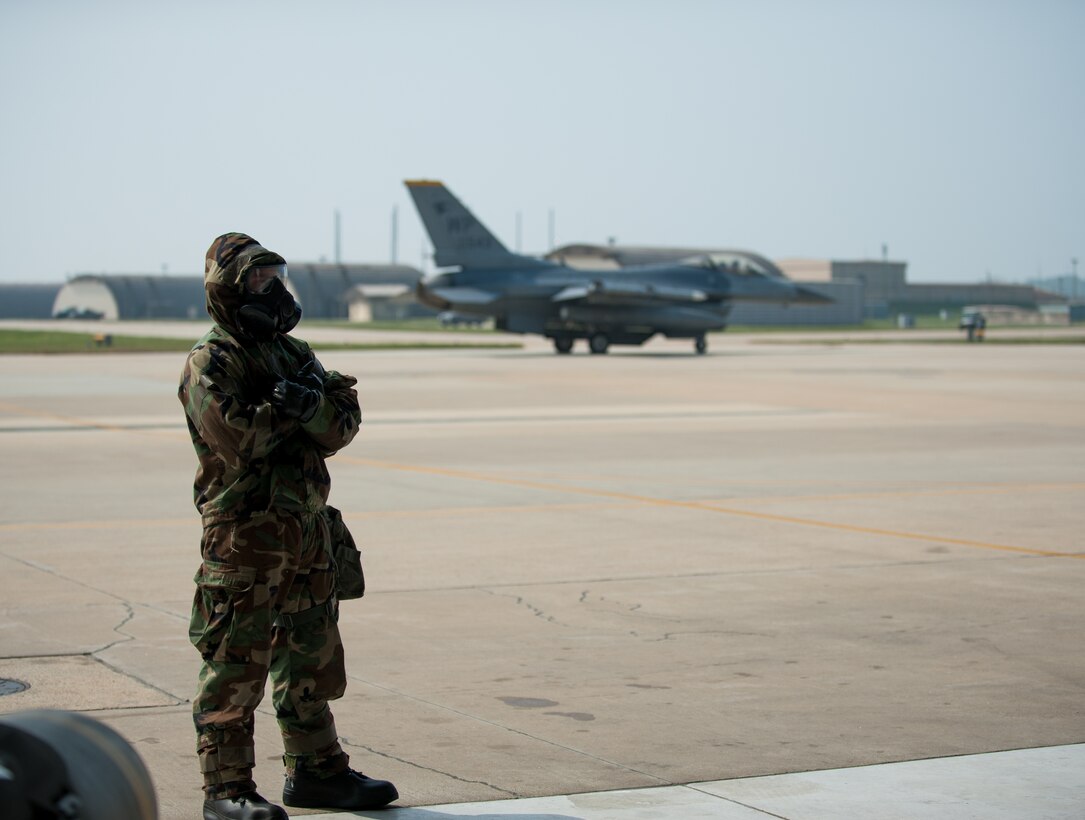 Airman 1st Class Christopher Sisk, 8th Aircraft Maintenance Squadron weapons load crew two-person, directs an F-16 during exercise Beverly Bulldog 14-2 at Kunsan Air Base, Republic of Korea, May 9, 2014. This exercise tested the Wolf Pack's ability to perform its mission while under threat of chemical attack. (U.S. Air Force photo by Staff Sgt. Clayton Lenhardt/Released)