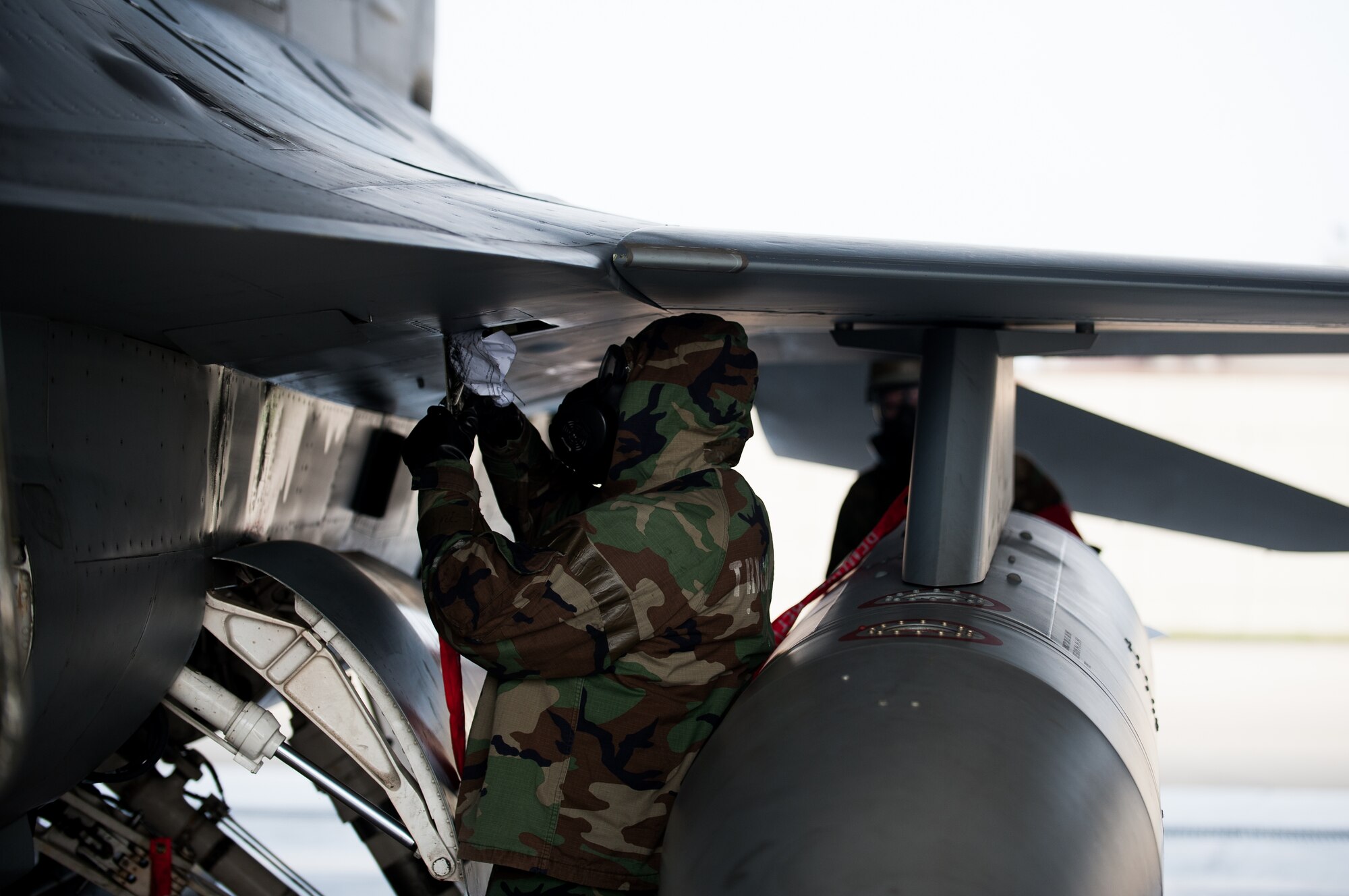 Senior Airman Brendan Walsh, 8th Aircraft Maintenance Squadron crew chief, inspects an F-16 during exercise Beverly Bulldog 14-2 at Kunsan Air Base, Republic of Korea, May 9, 2014. This exercise tested the Wolf Pack's ability to perform its mission while under threat of chemical attack. (U.S. Air Force photo by Staff Sgt. Clayton Lenhardt/Released)