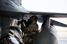 Senior Airman Brendan Walsh, 8th Aircraft Maintenance Squadron crew chief, inspects an F-16 during exercise Beverly Bulldog 14-2 at Kunsan Air Base, Republic of Korea, May 9, 2014. This exercise tested the Wolf Pack's ability to perform its mission while under threat of chemical attack. (U.S. Air Force photo by Staff Sgt. Clayton Lenhardt/Released)