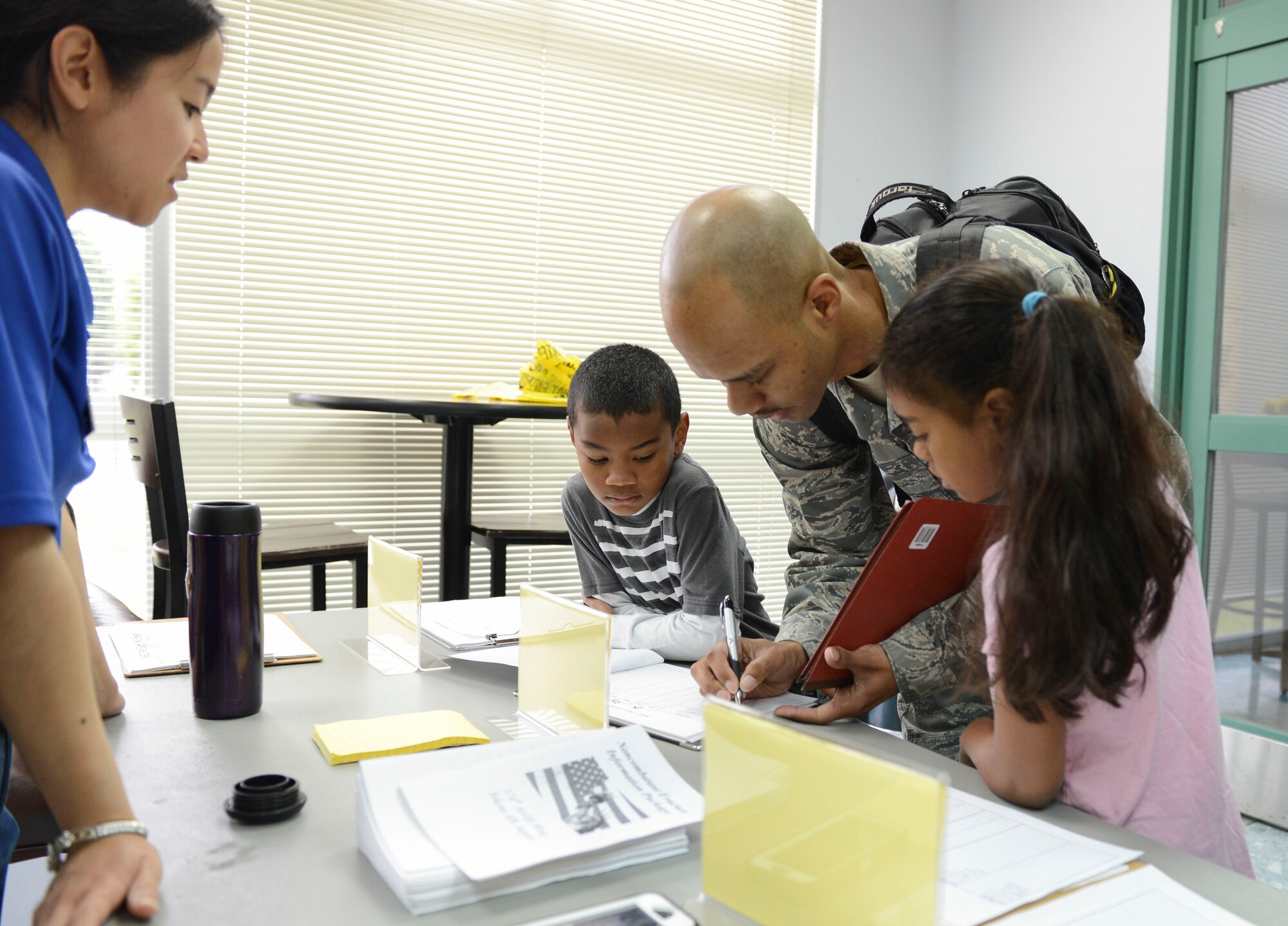 Tech Sgt. Terreil Reed, 730th Air Mobility Squadron unit training manager, signs in at the Taiyo Community Center with his family during a non-combatant evacuation exercise at Yokota Air Base, Japan, May 13, 2014.  In the event of an actual emergency requiring an evacuation, Yokota is postured to help execute a regional evacuation. (U.S. Air Force photo by Airman 1st Class Meagan Schutter/Released)