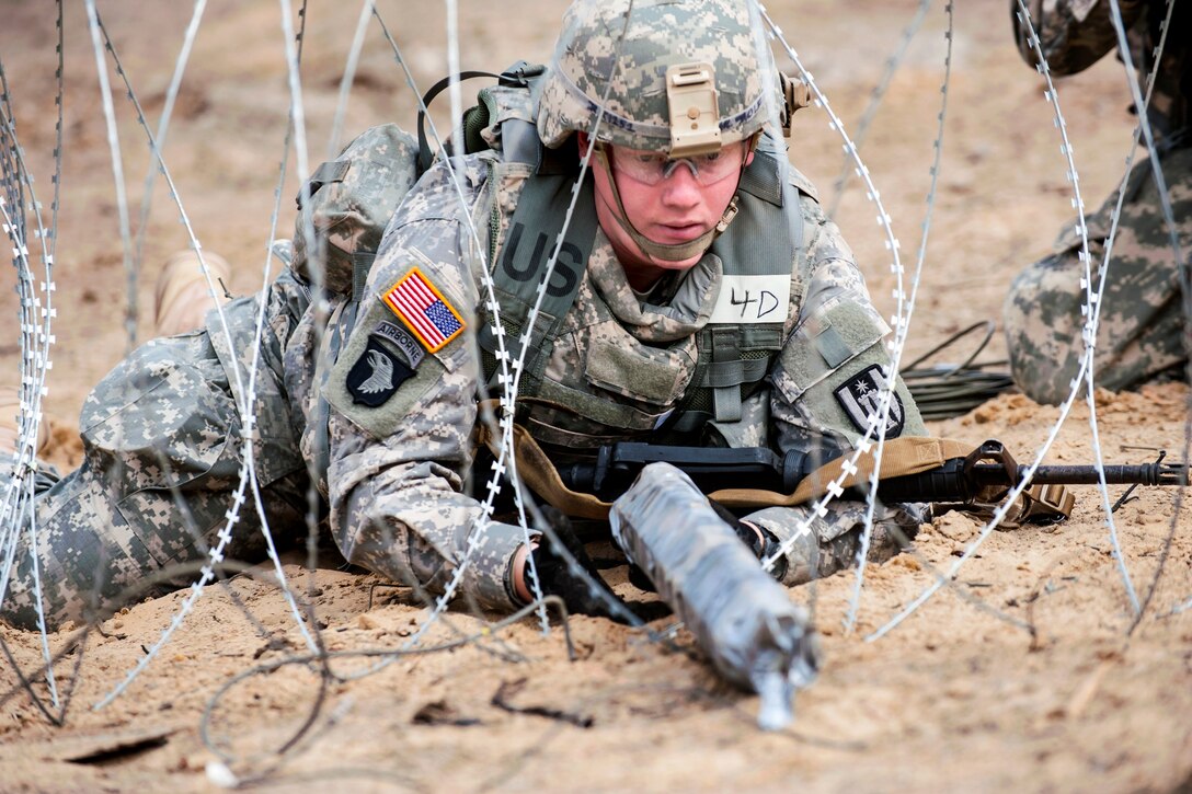 Army Spc. Ryan Rolf places C4 plastic explosive onto barbed wire during the offensive maneuver event at Sapper Stakes on Fort McCoy, Wis., May 5, 2014. Rolf is a combat engineer assigned to the 402nd Engineer Company.