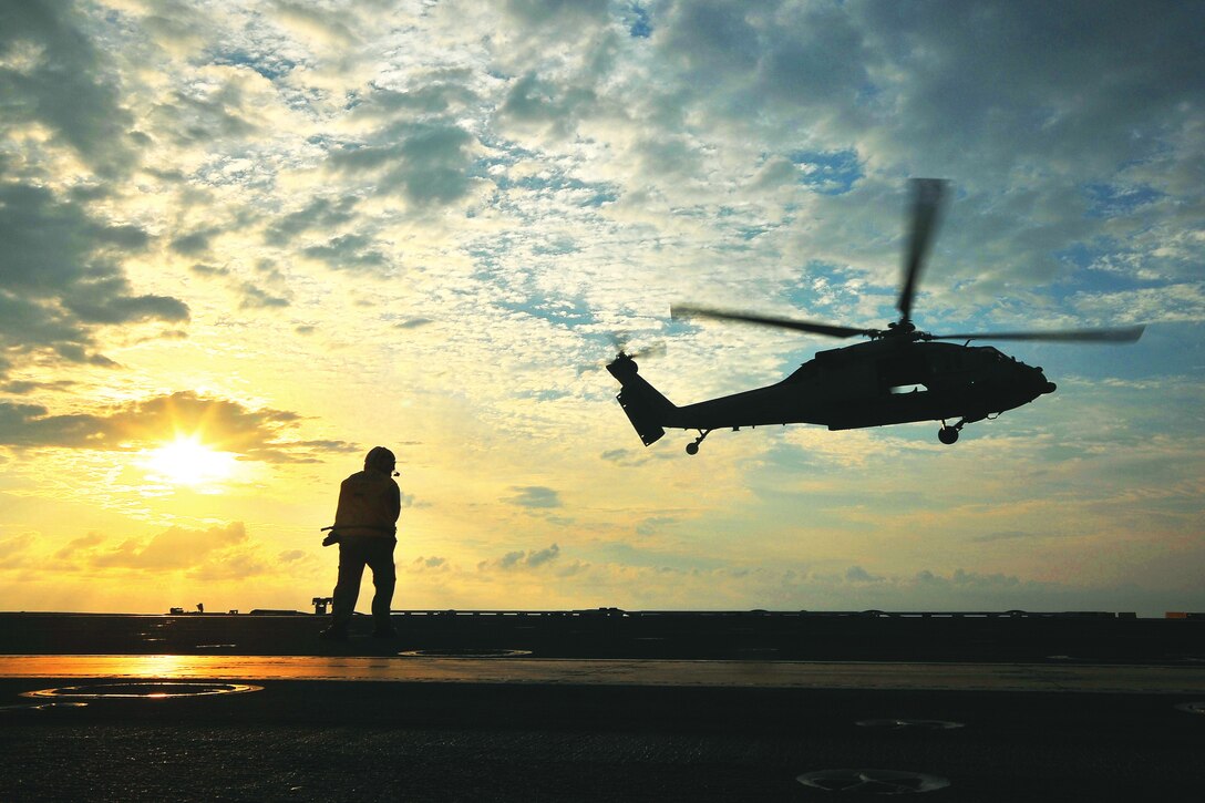 Navy Chief Petty Officer Jonard Sygaco monitors the departure of an MH-60S Sea Hawk helicopter from the flight deck of the USS George Washington in the Pacific Ocean, June 23, 2013. The George Washington and its embarked air wing, Carrier Air Wing 5, provide a combat-ready force that protects and defends the collective maritime interest of the United States and its allies and partners in the Indo-Asia-Pacific region.  
