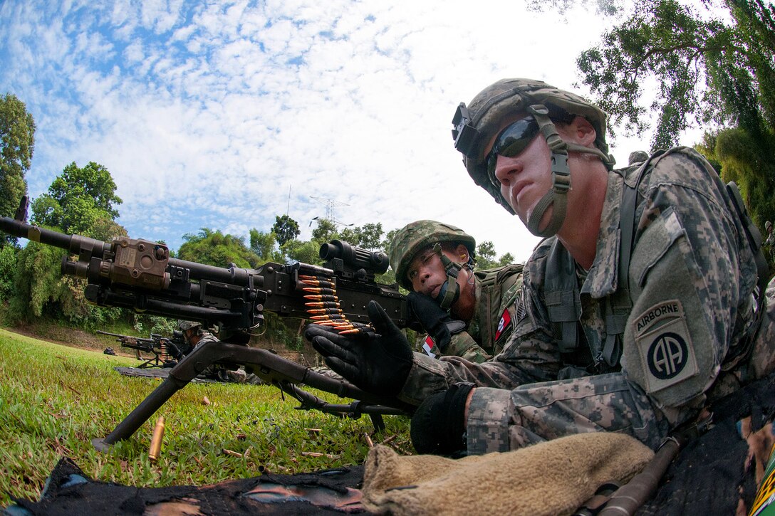 A U.S. paratrooper, right, helps an Indonesian army paratrooper prepare to fire an M240B machine gun during weapons training as part of exercise Garuda Shield 2013 at 1st Kostrad headquarters in West Java, Indonesia, June 14, 2013.  
