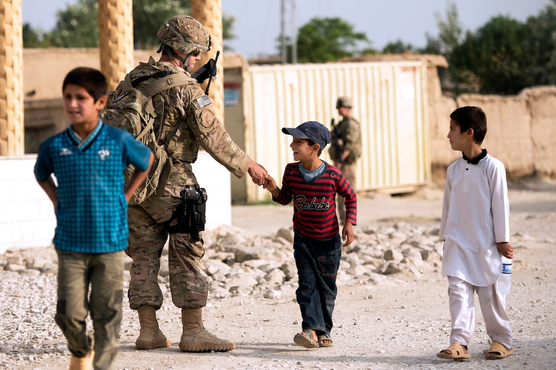 U.S. Air Force Staff Sgt. Michael Sweeney exchanges greetings with an Afghan boy while providing security in the town of Saka near Bagram Airfield in Parwan province, Afghanistan, June 13, 2013. Sweeney is assigned to the 455th Expeditionary Security Forces Group. U.S. airmen from that unit and the 577th Expeditionary Prime Base Engineer Emergency Force Squadron worked together to rebuild a road connecting Saka and Payan Janqadam.  
