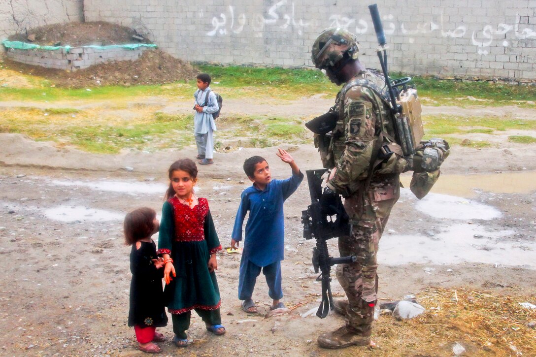 U.S. Army Sgt. Anthony Robinson interacts with a child while providing security during a meeting in Kajir Kheyl village in Afghanistan’s Khowst province, June 12, 2013. Robinson is assigned to the 101st Airborne Division's Company W, 2nd Battalion, 506th Infantry Regiment, 4th Brigade Combat Team. The U.S. soldiers have partnered with Afghan national security forces to establish relationships with key village elders and learn about the needs of residents.  
