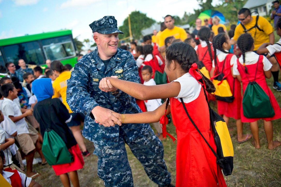 U.S. Navy Lt. John Tarr, a chaplain, and students from the Navutoka Government Primary School dance to a performance by the U.S. Navy Pacific Fleet Band during Pacific Partnership 2013 in Navutoka, Tonga, June 14, 2013. The exercise brings together host governments, the U.S. military, partner militaries and nongovernmental organization volunteers to prepare for disasters and build relationships in the Indo-Asia-Pacific region.  
