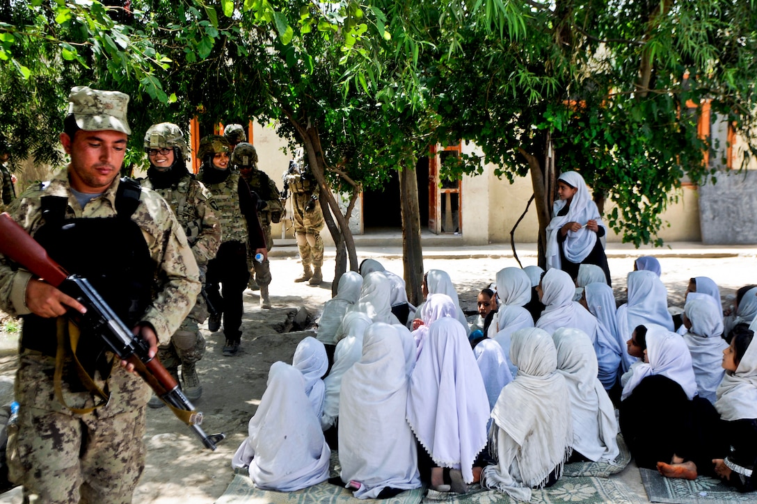 Afghan children watch as U.S. soldiers and Afghan national security forces enter their school to deliver humanitarian aid school supplies in Jalalabad City in Afghanistan’s Nangarhar province, May 25, 2013.  
