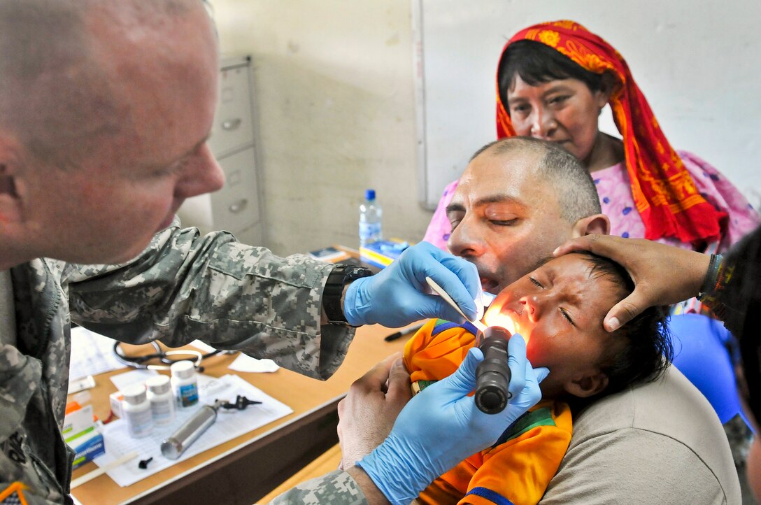 U.S. Army Maj. Matthew Brice, left, examines a child while U.S. Army Spc. Souheil Sarrouh provides comfort during medical training as part of Beyond the Horizon-Panama 2013 in Catina, Panama, May 29, 2013. The exercise, sponsored by U.S. Southern Command and led by U.S. Army South, deploys U.S. military engineers and medical personnel for training while providing humanitarian and civic assistance. Brice, a physician, and Sarrouh, a combat medic, are assigned to the 256th Combat Support Hospital.