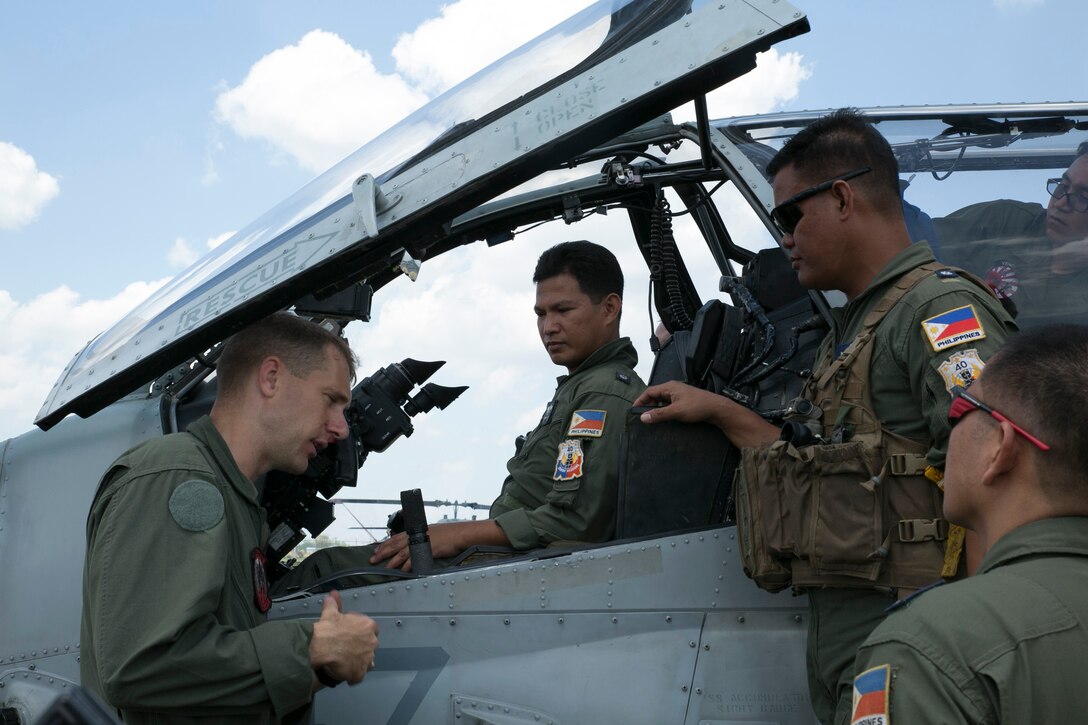 Capt. William Oren, far left, familiarizes members of the Philippine Air Force with the Super Cobra before a flight during Balikatan, here May 12, 2014. Senior service members of the PAF rode in the front seat of the Cobra to compare how Marines conduct flight operations versus themselves. Balikatan, in its 30th iteration, is a bilateral exercise between the U.S. and the Republic of the Philippines and aims at building both nations interoperability during joint planning, contingency, humanitarian and disaster relief operations. Oren is an AH-1W attack pilot with Marine Light Attack Helicopter Squadron 469, Marine Aircraft Group 12, 1st Marine Aircraft Wing under the Unit Deployment Program. The PAF service members are McDonnell Douglas 520 Military Gunship pilots with the 18th Attack Squadron, 15th Strike Wing. The Super Cobra is with HMLA-469, MAG-12, 1st MAW.