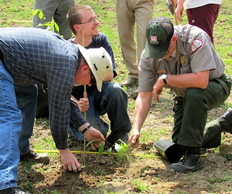 (Left to right) Keith Chasteen, Louisville District natural resources specialist, a Knott County Central High School Student, and Carr Creek Lake Ranger Kevin Wright plant a chestnut seedling as part of the initial planting at Carr Creek Lake's chestnut orchard on April 21, 2014. Additional planting will take place next spring in order to complete the orchard.
					