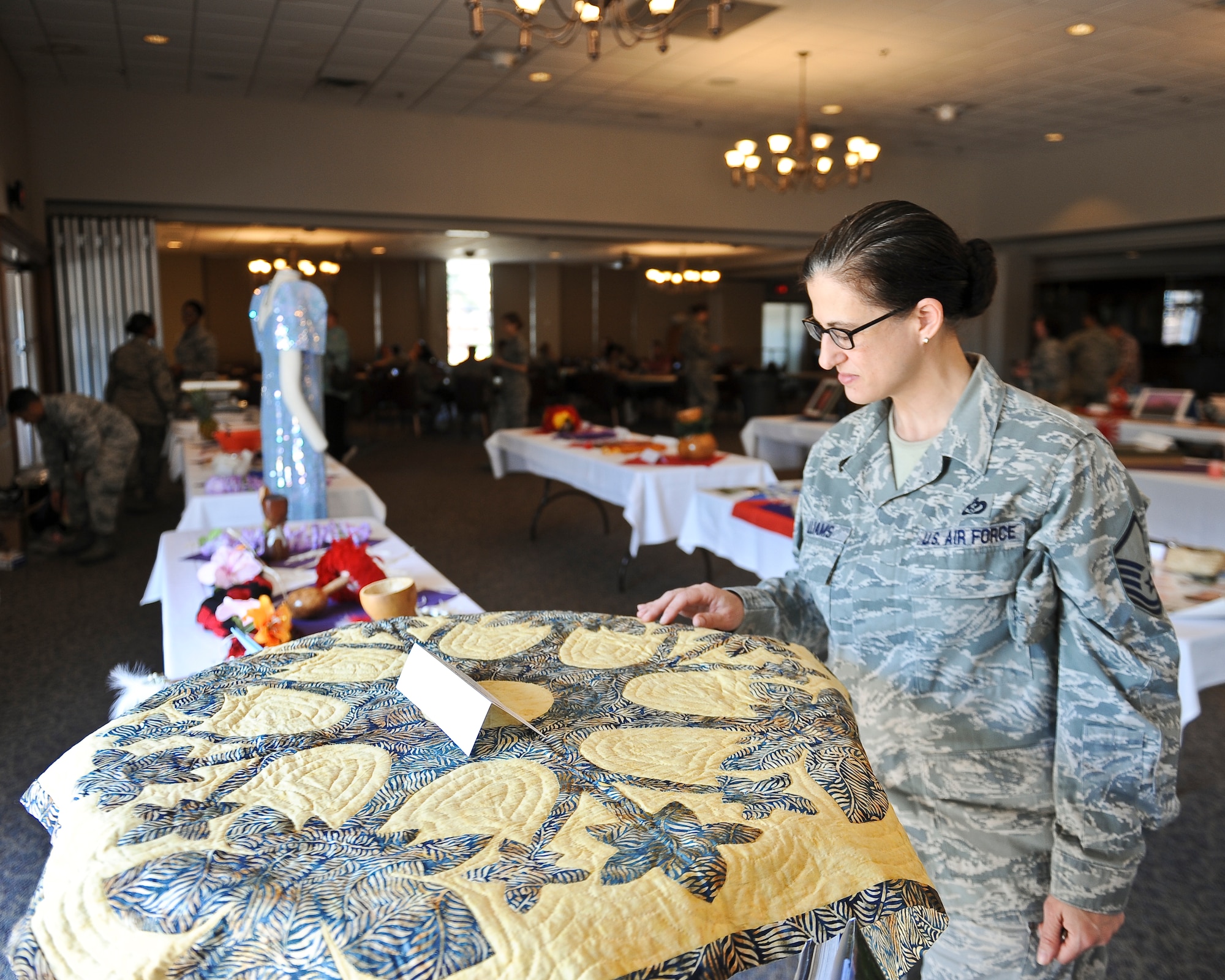 U.S. Air Force Master Sgt. Elizabeth Williams, 7th Civil Engineer Squadron, views a Hawaiian Naupaka quilt at the Tour of Asia and the Pacific Islands Art Expo May 8, 2014, at Dyess Air Force Base, Texas. The quilt was handmade in the design of a Naupaka flower, which is a shrub found in Hawaii’s mountains and near its beaches. (U.S. Air Force photo by Airman 1st Class Kedesha Pennant/Released)