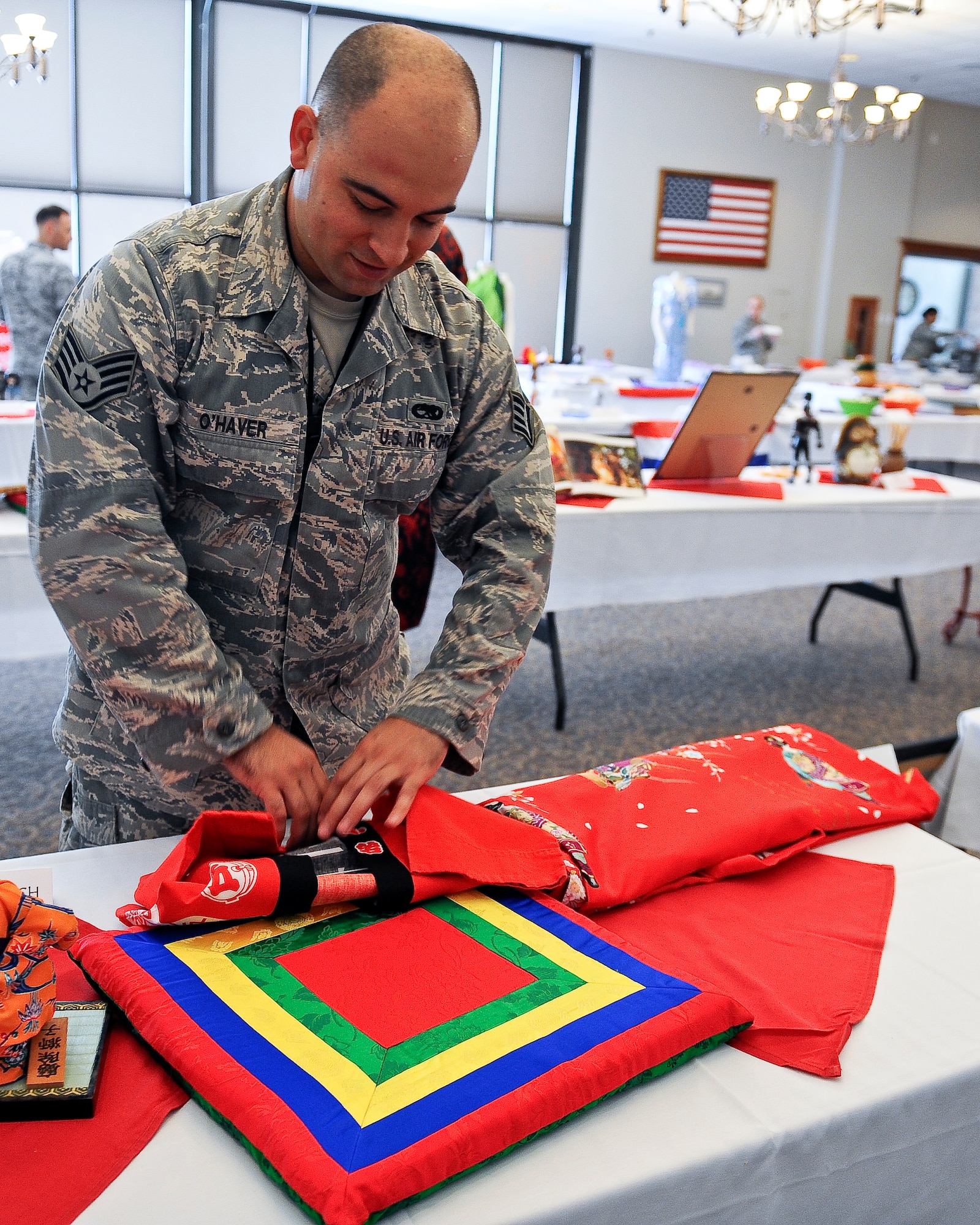 U.S. Air Force Staff Sgt. Richard O’Haver, 7th Operations Support Squadron cyber systems administrator, folds a Japanese happi coat at the Tour of Asia and the Pacific Islands Art Expo May 8, 2014, at Dyess Air Force Base, Texas.  A happi is a traditional Japanese straight-sleeved coat, usually imprinted with a distinctive crest and is primarily worn during festivals. O’Haver was stationed in Okinawa, Japan for four years, where he collected the coat and other traditional items. (U.S. Air Force photo by Airman 1st Class Kedesha Pennant/Released)