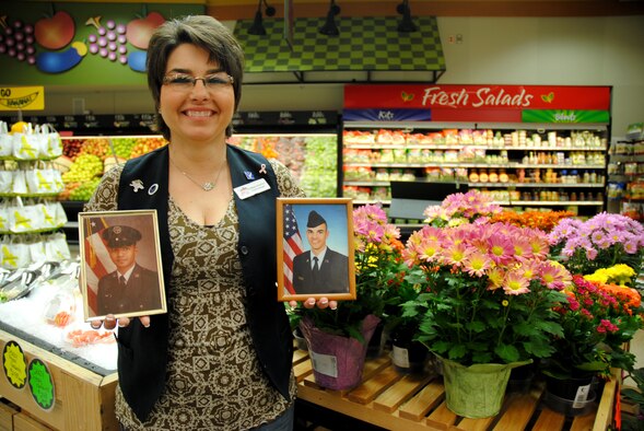 Donna Sharief, Grand Forks Air Force Base Commissary produce manager, proudly displays the photos of her husband, retired Tech. Sgt. Mohammed Sharief, and her son, Airman 1st Class Stephon Sharief, near the produce section of the commissary on Grand Forks AFB, N.D., on May 7, 2014. Mrs. Sharief served seven years in the Air Force as a surface freight specialist before joining the Defense Commissary Agency 13 years ago. The Church Hill, Tenn. native is the base’s Warrior of the Week for the third week of May 2014. (U.S. Air Force photo/Staff Sgt. Luis Loza Gutierrez) 
