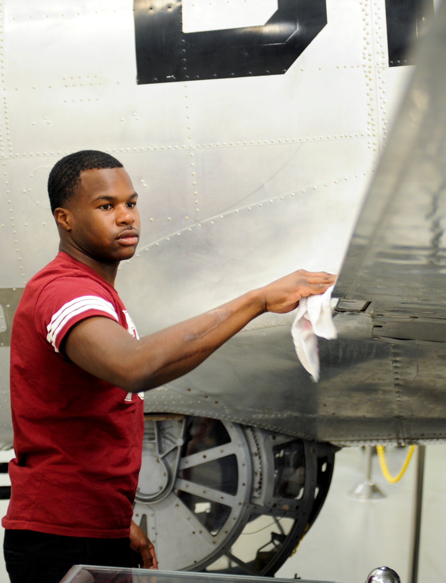 U.S. Air Force Airman 1st Class Keyon Mack, 357th Aircraft Maintenance Squadron crew chief, wipes down a wing of a B-17 Flying Fortress aircraft during a volunteer opportunity at the 390th Memorial Museum in Tucson, Ariz., May 10, 2014. Mack volunteered in order to interact with different World War II aircraft and learn more about the heritage of the B-17. (U.S. Air Force photo by Senior Airman Sivan Veazie/Released)