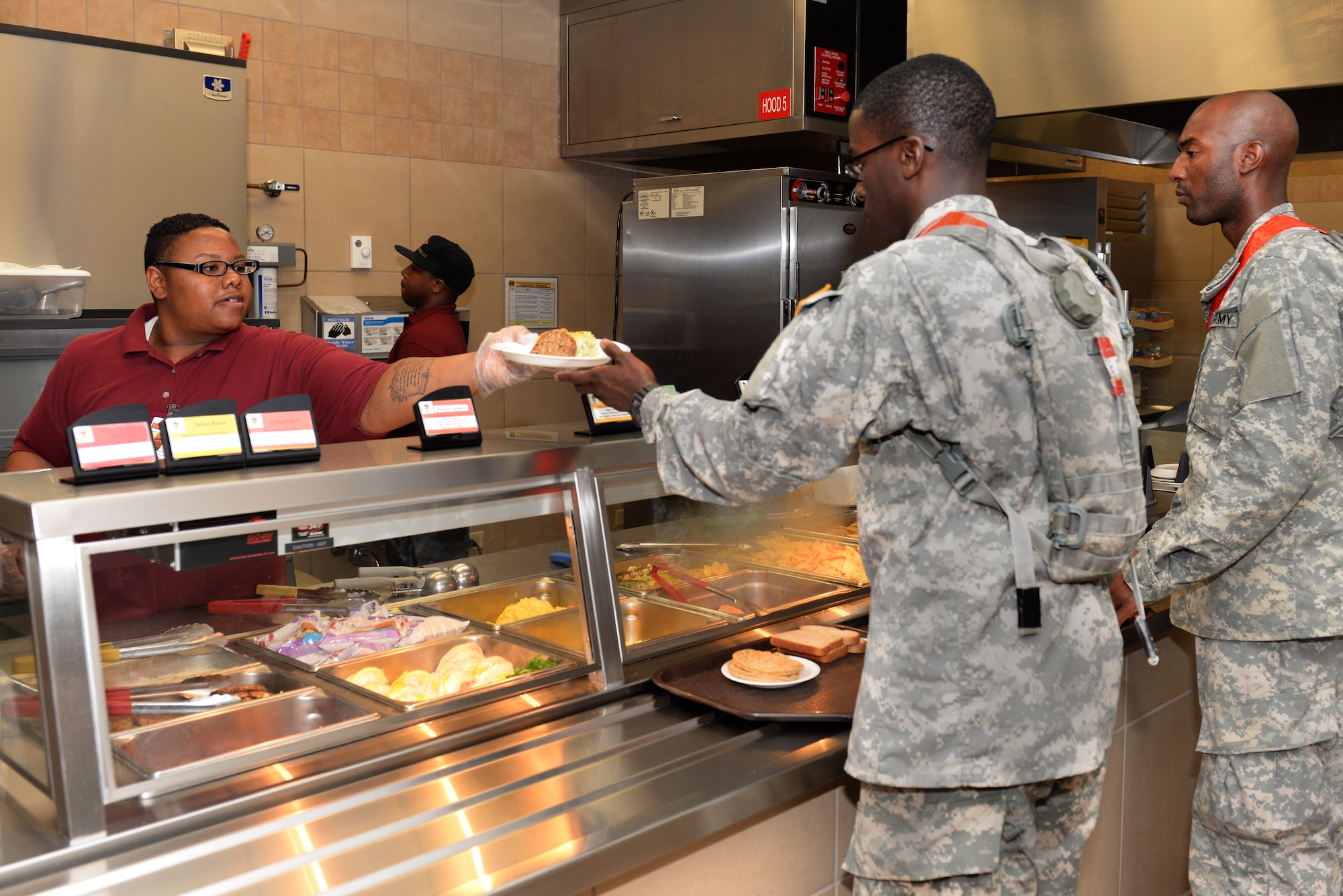 Jasmine Smith, a Warriors’ Café employee, serves breakfast to 128th Aviation Brigade Advanced Individual Training students at Fort Eustis, Va., May 13, 2014. The Warriors’ Café staff serves approximately 1,300 students at eight different meal times daily. (U.S. Air Force photo by Senior Airman Teresa J.C. Aber/Released)