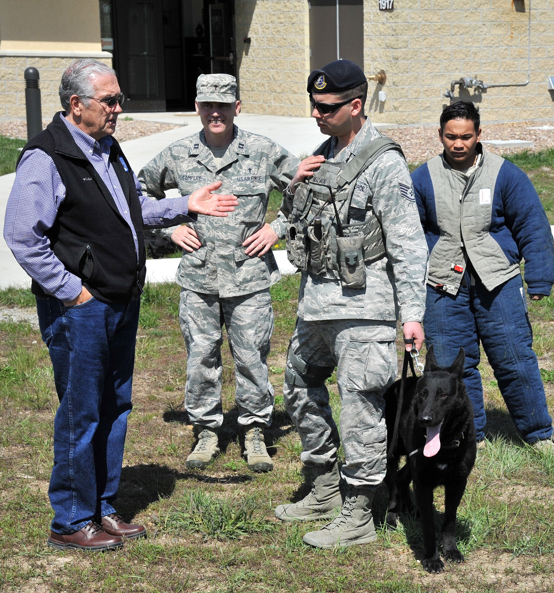 Dave Price (left) talks with Staff Sgt. David Nierzwicki, 341st Security Forces Squadron military working dog handler, and Zsabi, 341st SFS military working dog, May 13 following a dog team demonstration that was part of Clergy Day activities. Chaplain (Capt.) Robert Compere, 341st Missile Wing chaplain, and Senior Airman Storm Doromal, 341st SFS military working dog handler (far right), look on.  (U.S. Air Force photo / John Turner)