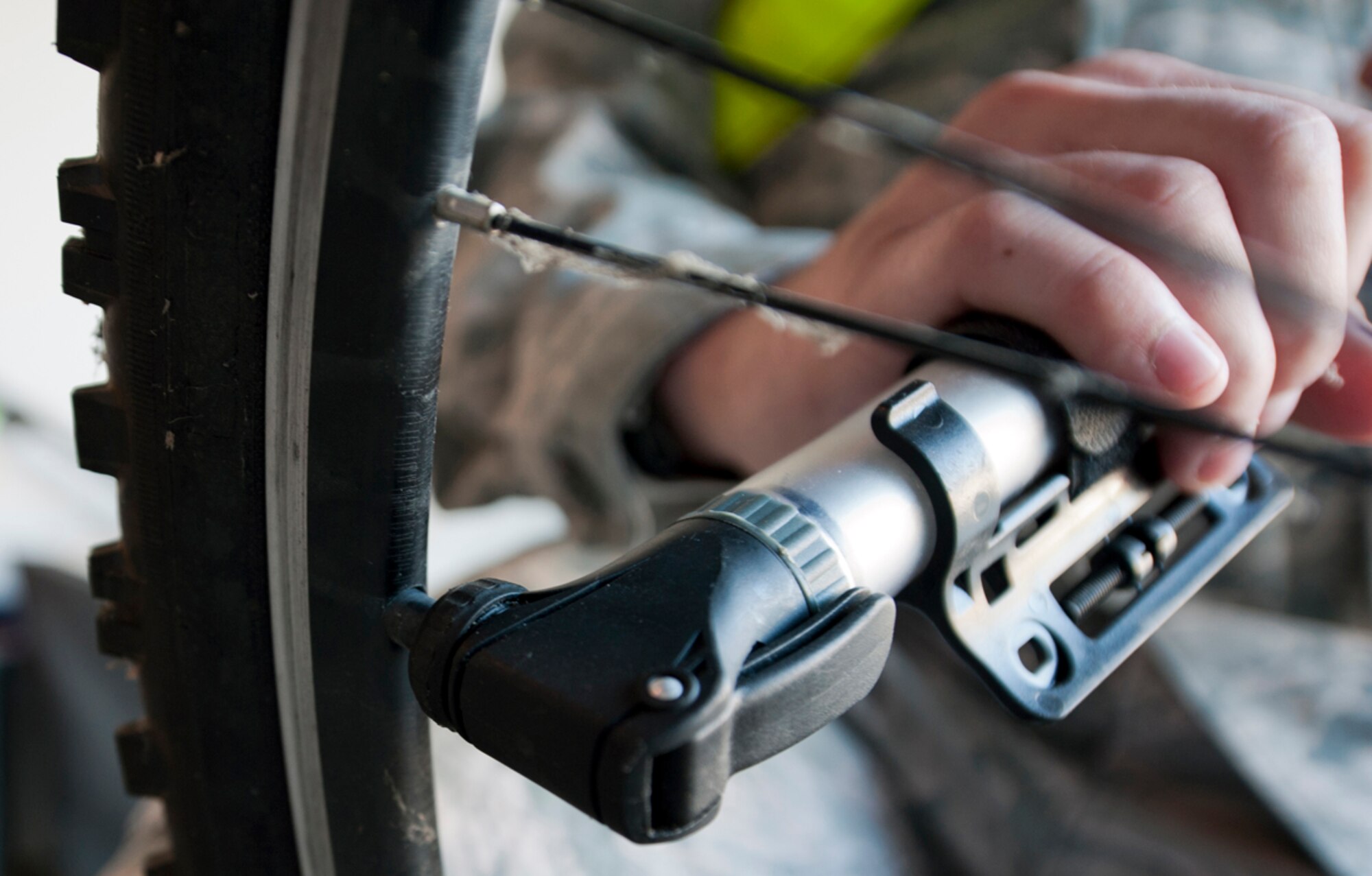 An Airman airs up his bicycle tire before going to work on Joint Base Elmendorf-Richardson, Alaska, May 10, 2014. Individuals who ride their bicycles on or off base should always take precautions while riding. Wearing a helmet while riding a bicycle is required at all times on JBER. Having a brightly colored T-shirt or safety belt, proper footwear and using appropriate reflectors on bicycles are some of the safety precautions individuals must adhere to while operating a bicycle both on or off base. (U.S. Air Force photo/Airman 1st Class Tammie Ramsouer)