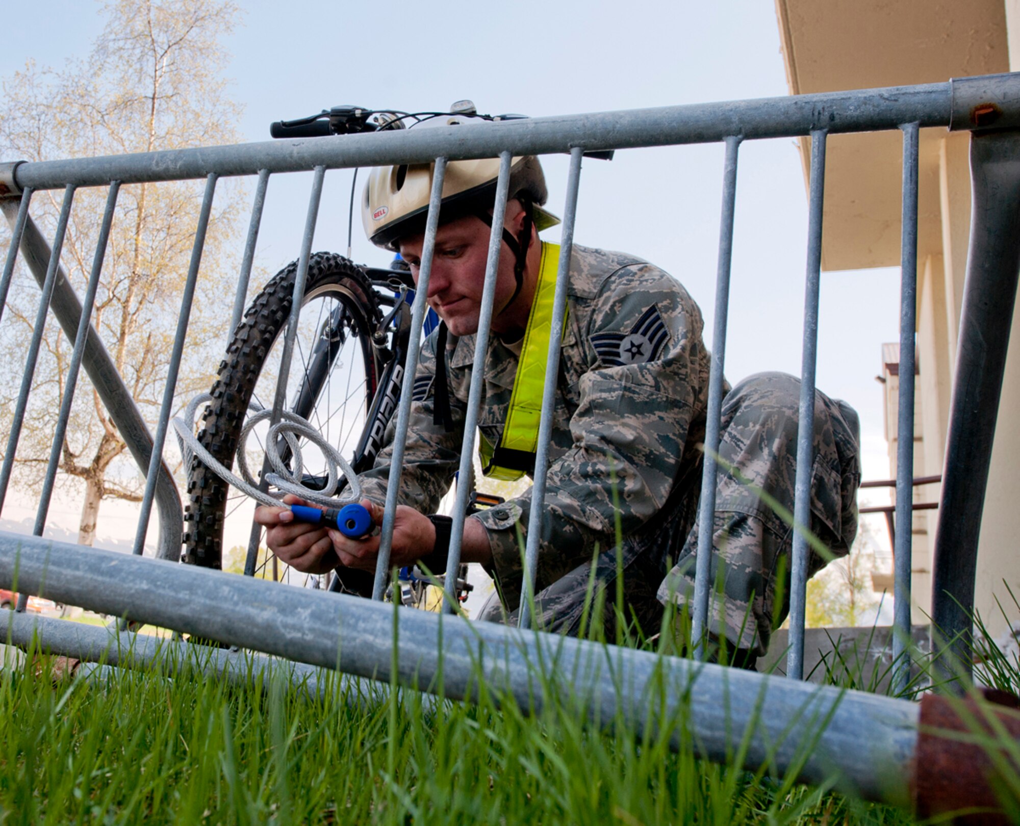 Air Force Staff Sgt. Robert Barnett, 673d Air Base wing Public Affairs photojournalist, locks his bicycle to a bike rack on Joint Base Elmendorf-Richardson, Alaska, May 13, 2014. Individuals who ride their bicycles on or off base must adhere to all traffic laws. Wearing a helmet at all times, having a brightly colored T-shirt or safety belt, proper footwear and using appropriate reflectors on bicycles are some of the safety precautions individuals must adhere to while operating a bicycle. (U.S. Air Force photo/Airman 1st Class Tammie Ramsouer)
