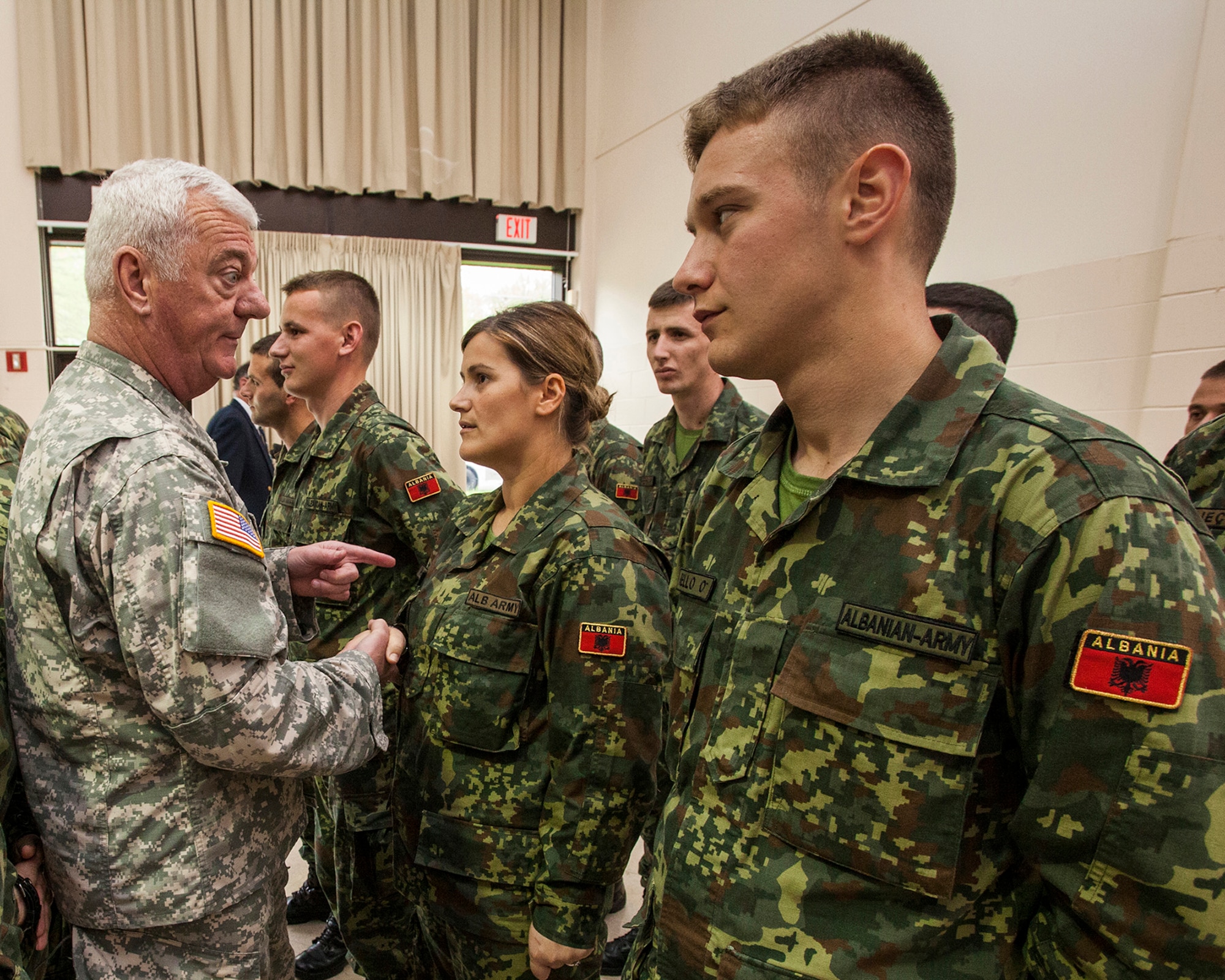Cadet Renalda Manushi shows another Republic of Albania Officer Candidate how to properly wear hat before the welcome ceremony the 24 cadets May 9, 2014, at Joint Base McGuire-Dix-Lakehurst, N.J. New Jersey Lt. Gov. Kim Guadagno, Brig. Gen. Michael L. Cunniff, The Adjutant General of New Jersey,  along with the New Jersey National Guard leadership welcome Albanian officer candidates of Albanian Officer Candidate Class 1 at the National Guard Joint Force Headquarters. Albania is the first State Partnership Program country to send its officer candidates to the United States to attend an Officer Candidate School program. The 12-week New Jersey Army National Guard OCS program is modelled after the active-duty program at Fort Benning, Ga., and includes classroom instruction, physical and leadership training. (U.S. Air National Guard photo by Master Sgt. Mark C. Olsen/Released)