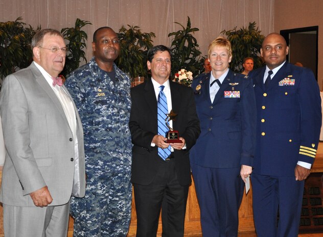 The Lowcountry Federal Healthcare Alliance was awarded the Federal Employee of the Year Team Award during the Federal Executive Association of the Greater Charleston Area annual Employee of the Year luncheon May 13, at the Red Bank Club on Joint Base Charleston. Navy Capt. Marvin Jones, Naval Health Clinic Charleston commanding officer (second from left), Scott Isaacks, LFHA chairman and interim director of the Ralph H. Johnson VA Medical Center (center), and Col. Judith Hughes, 628th Medical Group commander, accepted the award on behalf of LFHA, a joint venture partnership between DOD and VA healthcare entities to coordinate and share healthcare resources in order to improve access to quality and cost-effective healthcare for all their beneficiaries. The LFHA includes Naval Health Clinic Charleston, Ralph H. Johnson VA Medical Center, 628th Medical Group and Naval Hospital Beaufort. The Honorable Bill Collins (far left), Mayor of Summerville, gave the keynote address and Coast Guard Capt. Jason Merriweather (far right), chairman of Charleston Area FEA, introduced the keynote speaker at the luncheon. (U.S. Navy Photo/Kris Patterson)