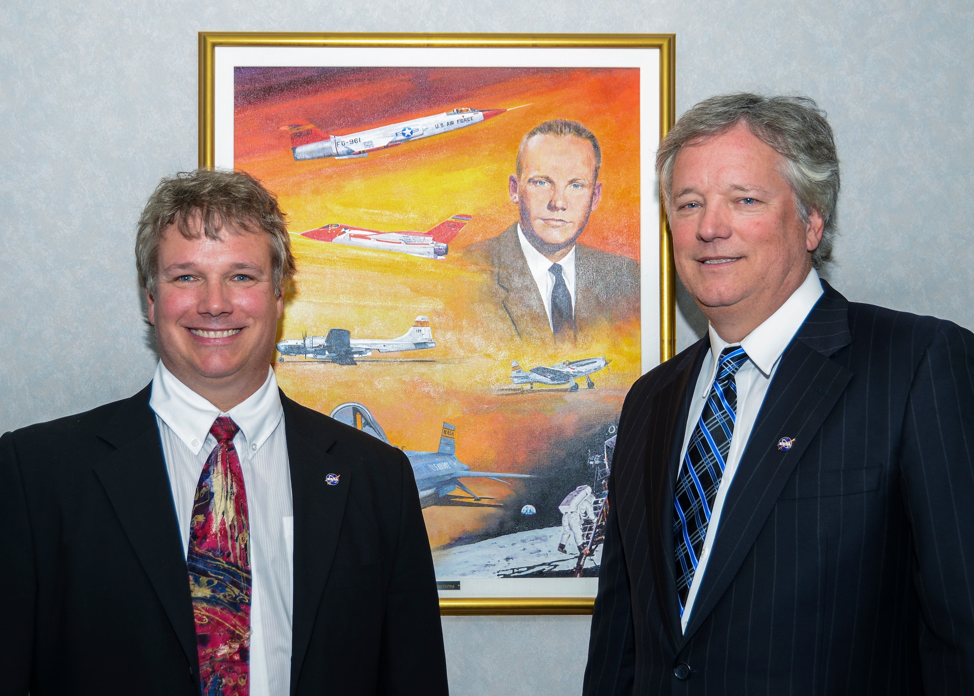 Mark Armstrong (left) and his brother Rick Armstrong are shown with a painting of their father, Neil Armstrong in Building 4800 at the Armstrong Flight Research Center. (U.S. Air Force photo by Rebecca Amber)