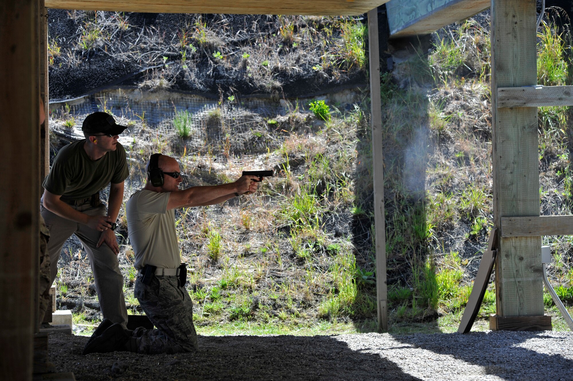 Maj Michael Melton, 381st Training Support Squadron operations officer, fires a round from a kneeling position under the supervision of his range safety officer Tech. Sgt. Ian Ramirez during the Law Enforcement Pistol Shoot May 13, 2014, Vandenberg Air Force Base, Calif. The pistol shoot was open to all military and local law enforcement officers as part of a National Police Week celebration at Vandenberg. (U.S. Air Force photo by Michael Peterson/Released)
