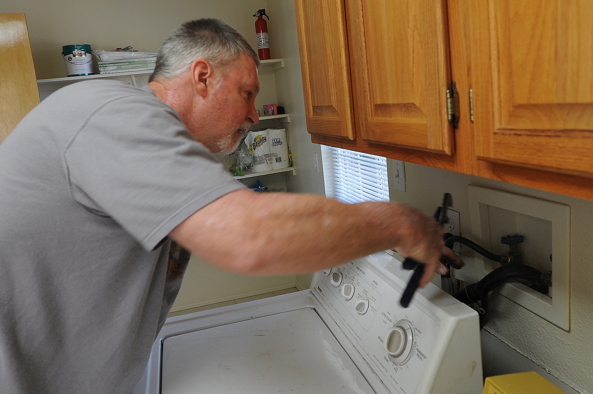 ALTUS AIR FORCE BASE, Okla. – Retired U.S. Air Force Tech. Sgt. Marshall Hermer, 97th Maintenance Directorate jet engine mechanic, installs a washer in an Airman’s house May 9, 2014. Hermer has restored, delivered and maintained more than 75 sets of washers and dryers in the past two years as part of the Altus Armed Services YMCA Washer and Dryer Program that gives junior enlisted Airmen restored laundry appliances for free. (U.S. Air Force photo by Senior Airman Levin Boland/Released)