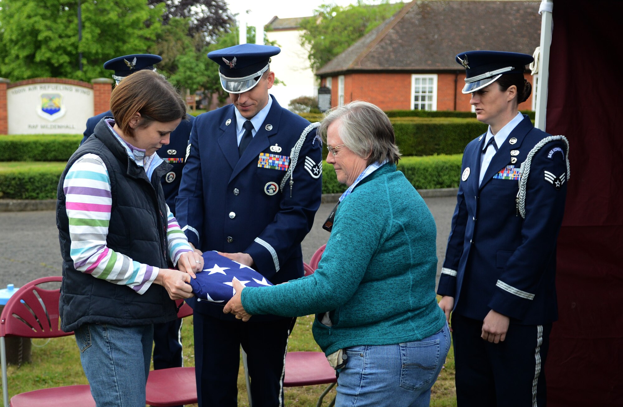 Stephanie Rose, left, wife of Inspector Matthew Rose, 100th Security Forces Squadron honorary commander, and Sian Wynn, wife of Retired Royal Air Force Air Cdre. Bruce Wynn, finish folding an American flag May 13, 2014, during the Honorary Commanders' Day Chip Challenge on RAF Mildenhall, England. The day included team building and informative activities, an induction ceremony, static aircraft displays and a retreat ceremony. (U.S. Air Force photo by Airman 1st Class Dillon Johnston/Released)
