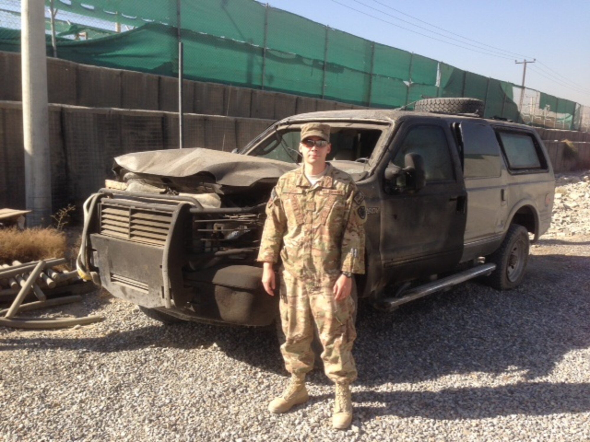 Tech. Sgt. Austin Hardin, Air Force Nuclear Weapons Center, stands next to a vehicle that was hit by a car bombing. Austin was knocked unconscious but was able to safely guide his team back to the base.  He was awarded the Purple Heart and Bronze Star medals. (Courtesy photo)