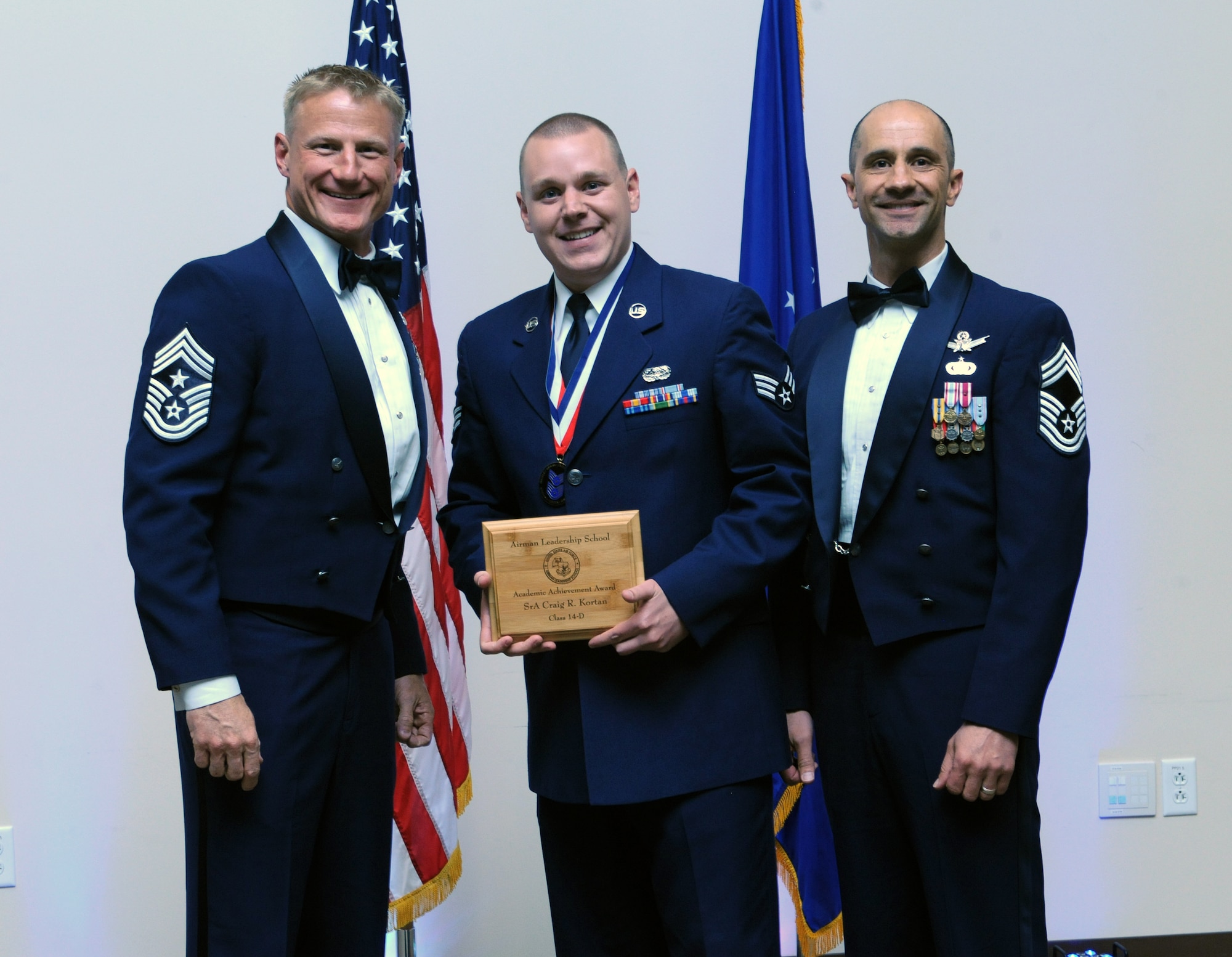 Senior Airman Craig Kortan, 460th Space Communication Squadron, center, receives the Academic Achievement Award during the Buckley Airman Leadership School Class 14-D graduation May 9, 2014, at the Leadership Development Center on Buckley Air Force Base, Colo. This award is presented to the student with the highest overall average on all academic evaluations during ALS. (U.S. Air Force photo by Airman Emily E. Amyotte/Released)