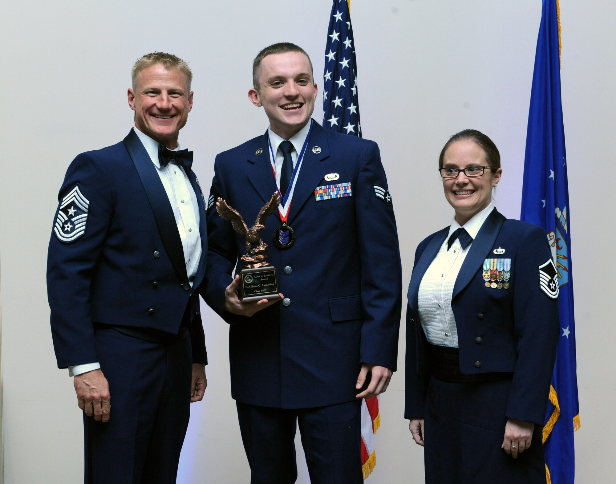 Senior Airman Sean Leming, 460th Logistics Readiness Squadron, center, receives the John L. Levitow Award during the Buckley Airman Leadership School Class 14-D graduation May 9, 2014, at the Leadership Development Center on Buckley Air Force Base, Colo. The Levitow award is given to the ALS graduate with the highest academic scores and leadership potential. (U.S. Air Force photo by Airman Emily E. Amyotte/Released)