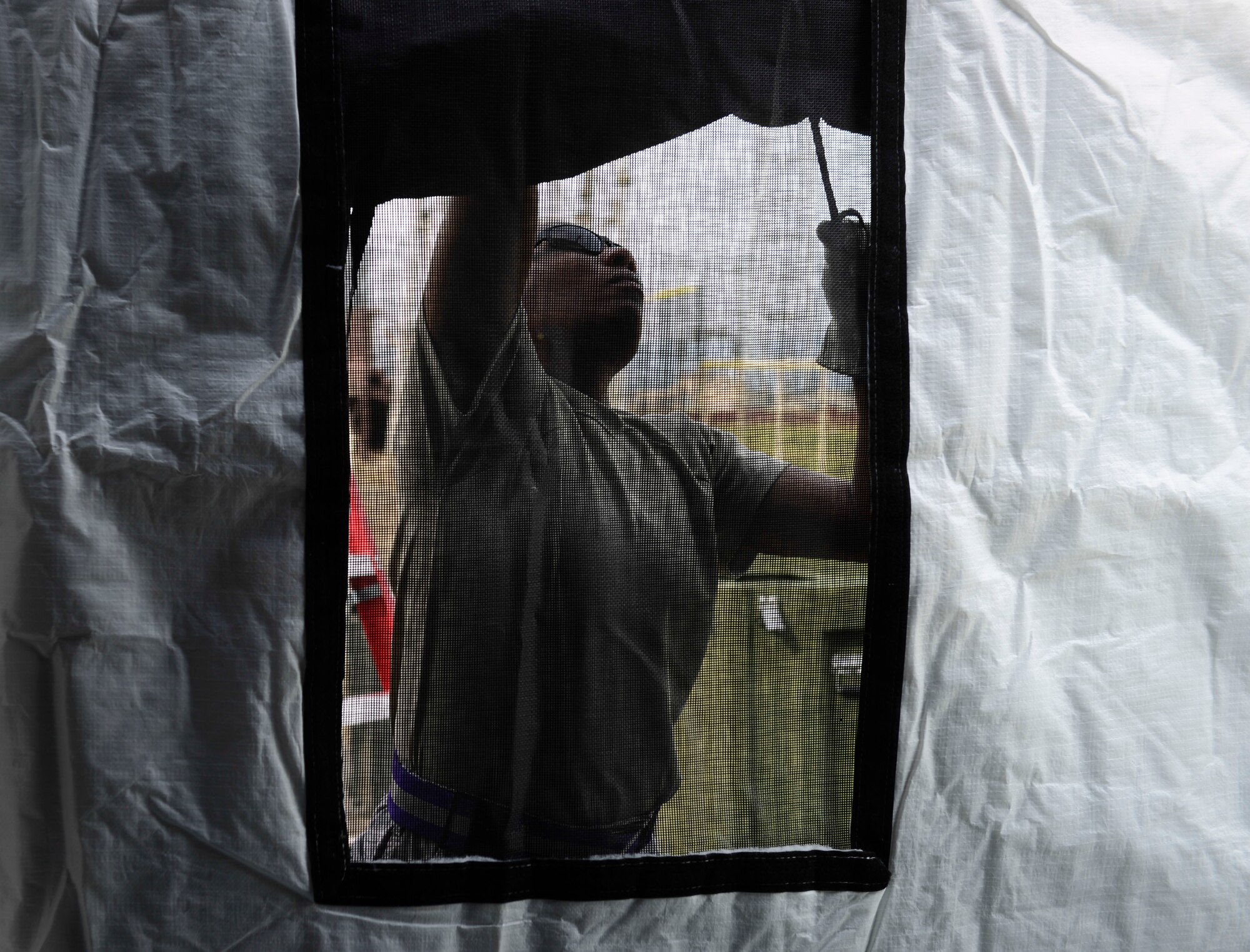 An Airman from the 374th Medical Group rolls up a window cover on an Expeditionary Medical Support tent at Yokota Air Base, Japan, May 14, 2014.  An EMEDS team has a anesthesiologist, orthopedic surgeon, emergency room doctor, operating room nurse and a general surgeon to treat patients in a contingency. (U.S. Air Force photo by Airman 1st Class Meagan Schutter/Released)