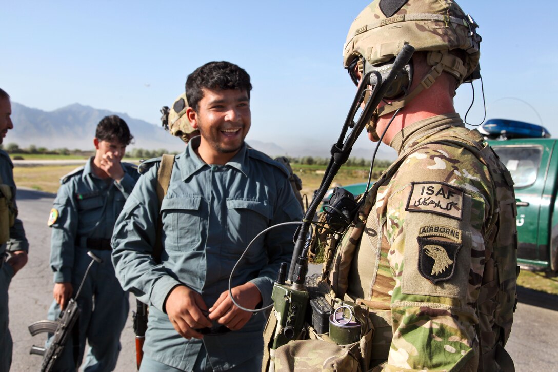 U.S. Army Staff Sgt. Mark Reed greets an Afghan uniformed policeman before a humanitarian assistance mission near Bagram city in Afghanistan's Parwan province, May 2, 2014.  Reed is assigned to the 101st Airborne Division's 1st Battalion, 75th Cavalry Regiment.