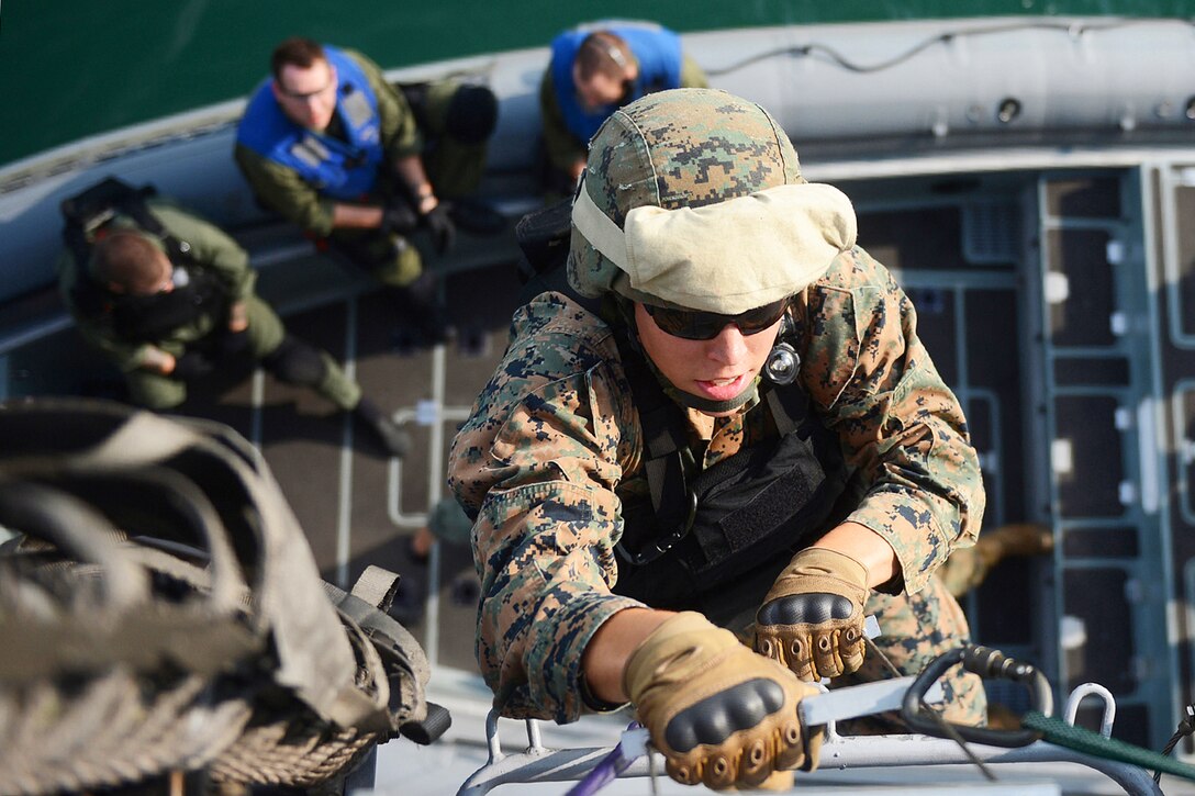 Marine Corps Lance Cpl. Darren Clay uses a ladder to board the littoral combat ship USS Freedom during a joint visit, board, search and seizure exercise in Singapore, June 11, 2013. The Freedom is in Singapore on an overseas deployment.  
