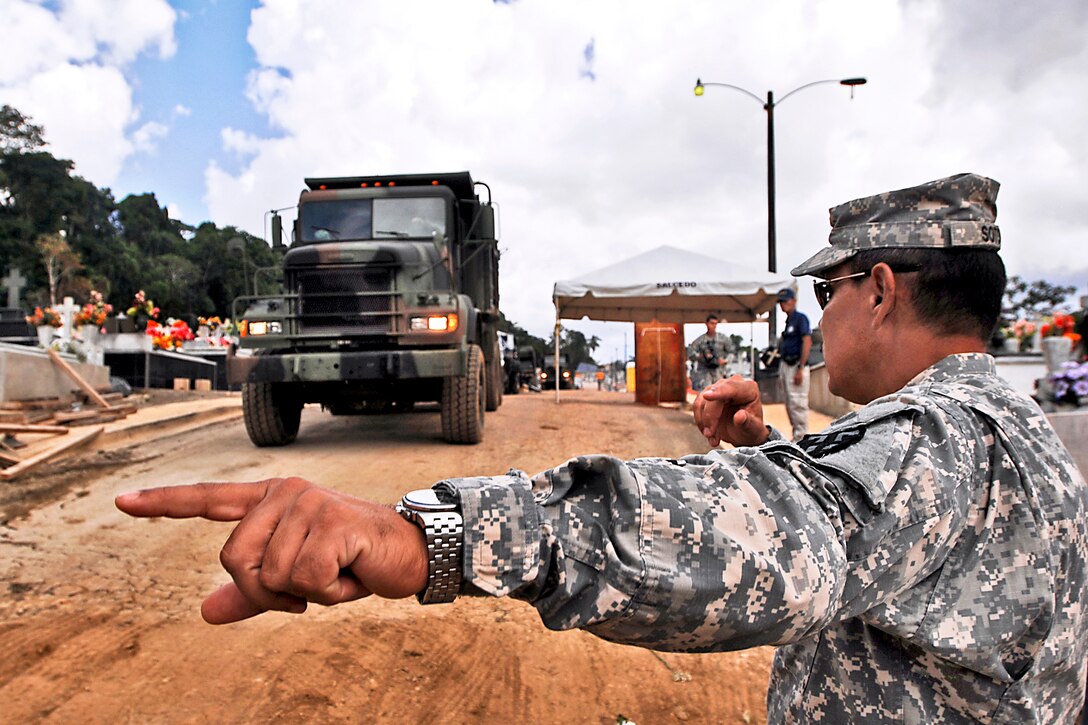 A U.S. soldier directs the driver of a dump truck before delivering a load of top soil to a work site affected by heavy rains in Lares, Puerto Rico, May 29, 2013.  
