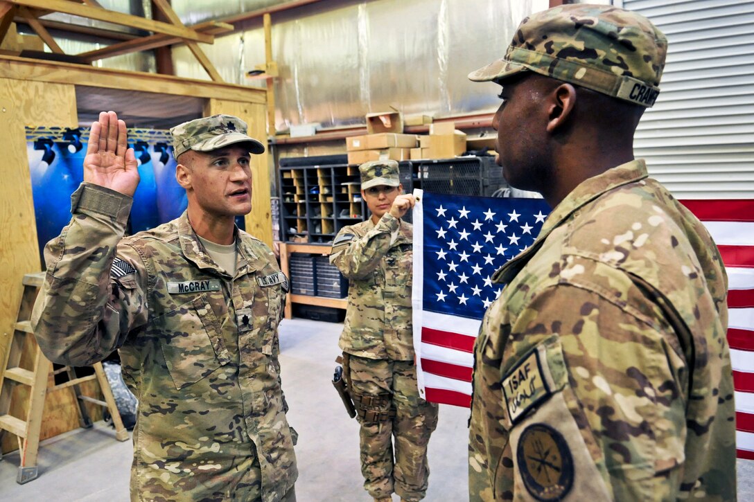 U.S. Navy Cmdr. Louis McCray, left, administers the oath of enlistment to U.S. Navy Chief Petty Officer Al Crawford during a re-enlistment ceremony on Forward Operating Base Farah, Afghanistan, June 1, 2013. McCray is the commanding officer of Provincial Reconstruction Team Farah, and Crawford, an operations specialist, is assigned to the Farah team.  
